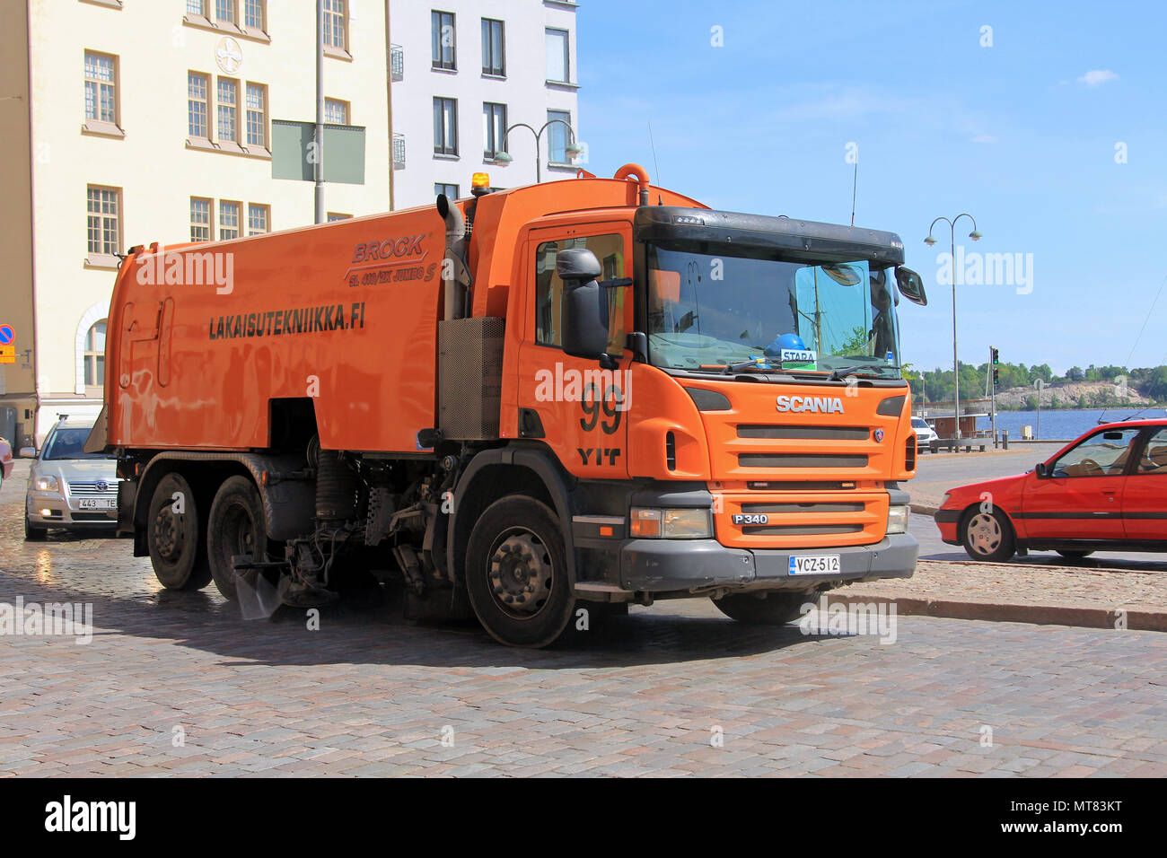 Scania P340 Orange road sweeper nettoie ville rue parmi le trafic sur une journée ensoleillée de printemps à Helsinki, Finlande - le 24 mai 2018. Banque D'Images