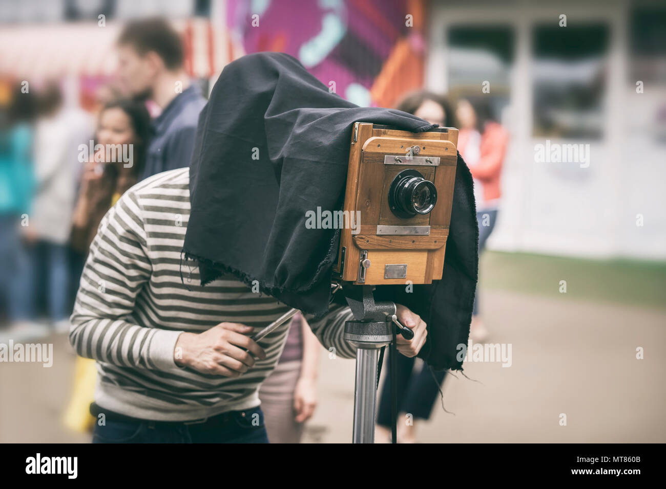 Photographe avec appareil photo en bois vintage antiquité sous cape foncée en photographiant les passants - ancienne action classique, rareté concept Banque D'Images