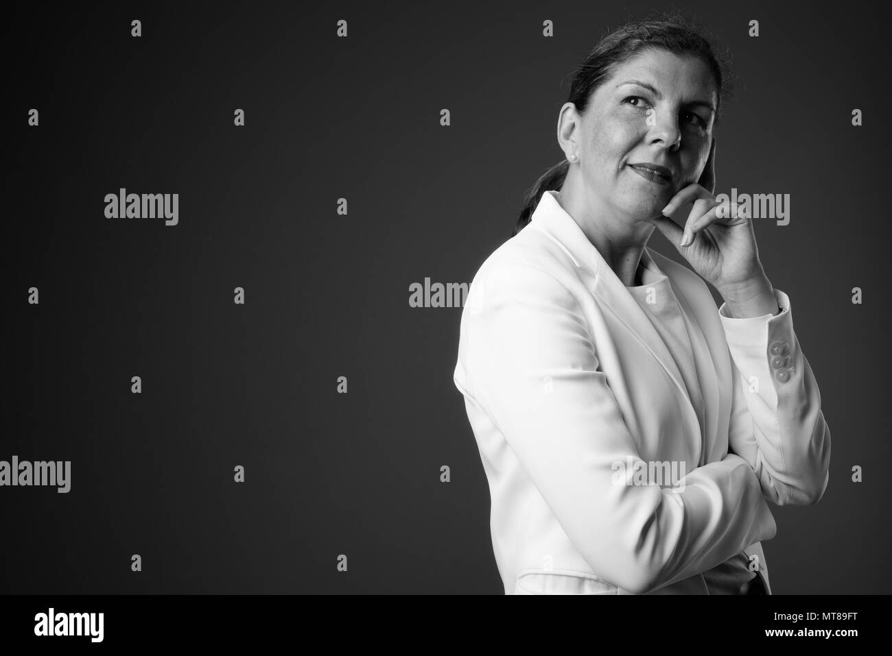 Belle mature businesswoman contre l'arrière-plan gris en noir Banque D'Images