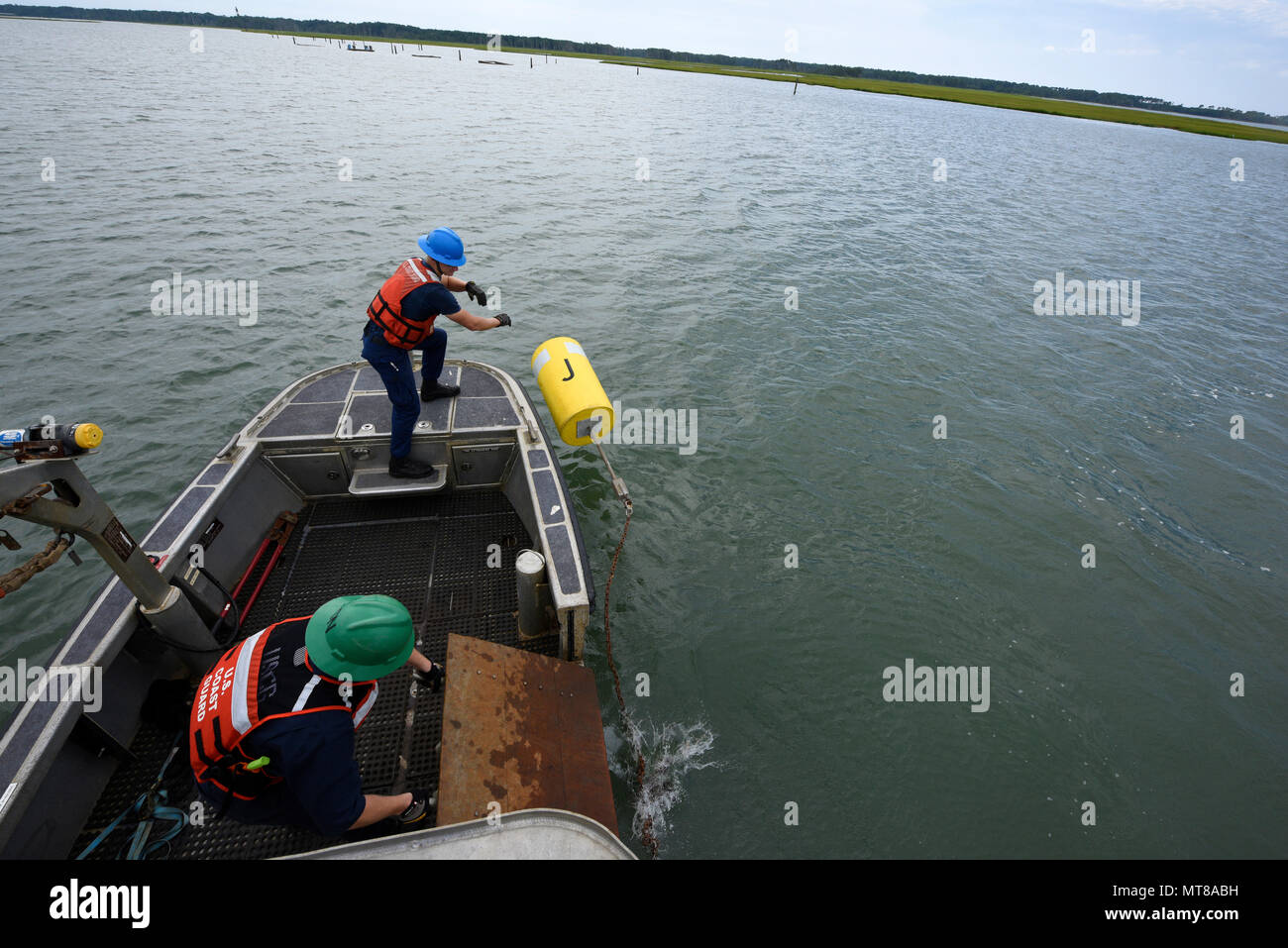 Garde côtière canadienne Maître de 2e classe Jonathan Folger et Christopher Seaman Moïse, membres de l'équipage à l'équipe d'aides à la navigation Chincoteague, Virginie, supprimer une bouée dans l'Assateague Channel, le 24 juillet 2017. L'équipage de Chincoteague ANT des bouées utilisées pour marquer un périmètre de sécurité pour les spectateurs lors de la 92e assemblée annuelle Poney Chincoteague nager. (U.S. Photo de la Garde côtière canadienne par le maître de 3e classe/Zilnicki Corinne libéré) Banque D'Images