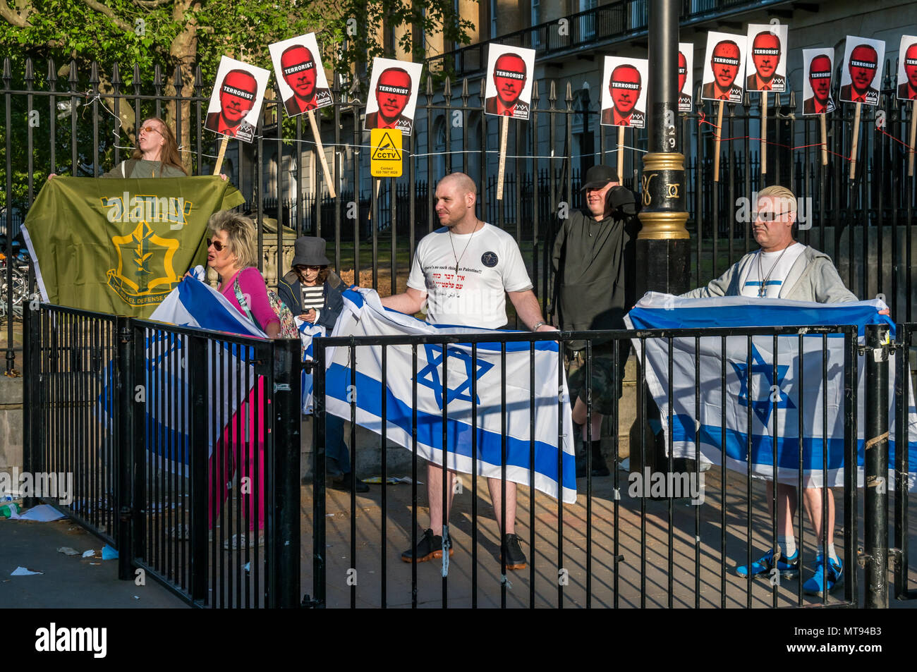 15 mai 2018 - Hier, les manifestants qui ont entraîné 58 décès et plus de 2700 blessés graves, avec une poignée de sionistes vague des drapeaux israéliens et soutenir les actions illégales des forces israéliennes. L'un avait une étoile de David tatoué sur son visage et un t-shirt à nier l'existence de la Palestine, et l'autre agité un drapeau de la Force de défense d'Israël. Les policiers ont encerclé par une double couche d'obstacles et se tint le long de l'extérieur d'eux, mais les autres manifestants ont été tout simplement les ignorer. Il n'était pas clair combien de cinq étaient juifs, mais il y avait beaucoup, beaucoup plus de Juifs à quelques mètres protestent contre un Banque D'Images