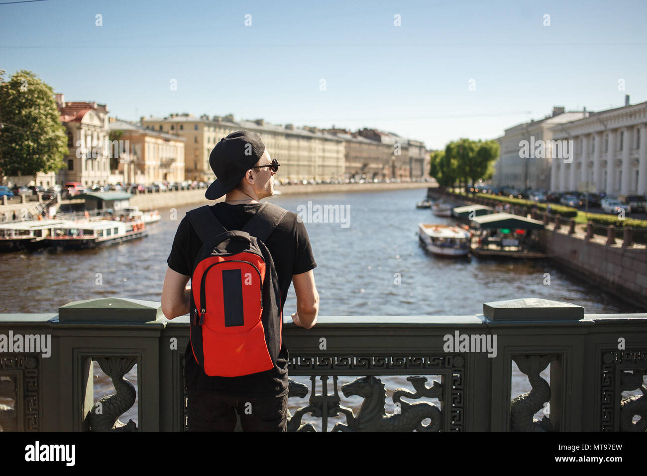 Homme élégant avec sac à dos à la recherche d'architecture sur le quai de canal Griboyedov à Saint-Pétersbourg, en Russie. Banque D'Images