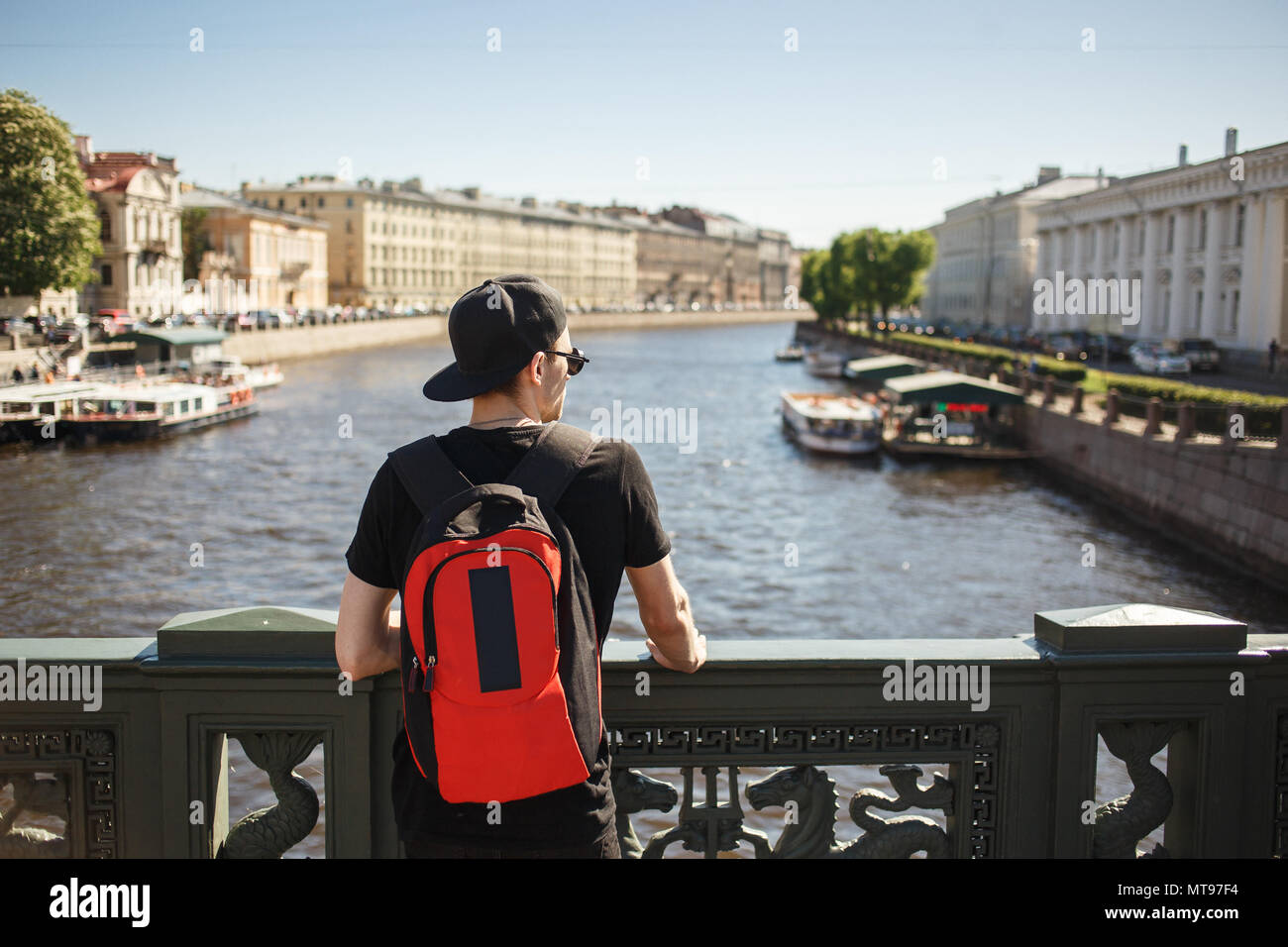 Homme élégant avec sac à dos à la recherche d'architecture sur le quai de canal Griboyedov à Saint-Pétersbourg, en Russie. Banque D'Images