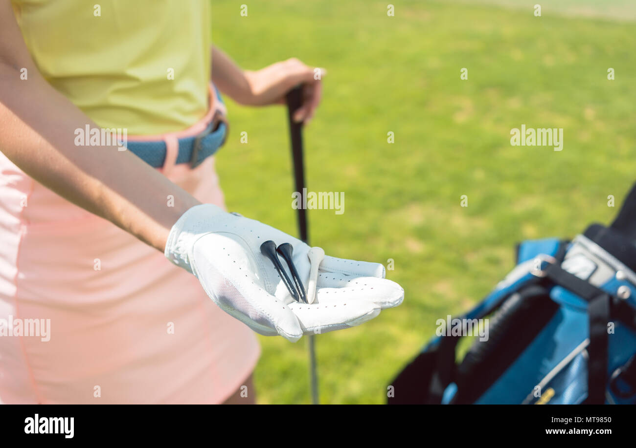 Détail de la main d'une femme tenant trois tees sur un terrain de golf Banque D'Images