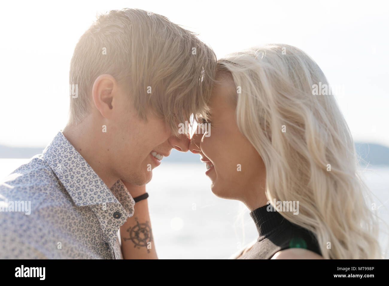 Beau flirter et smiling couple romantique à embrasser sur la plage au soleil. Flirt d'été à l'extérieur. Banque D'Images