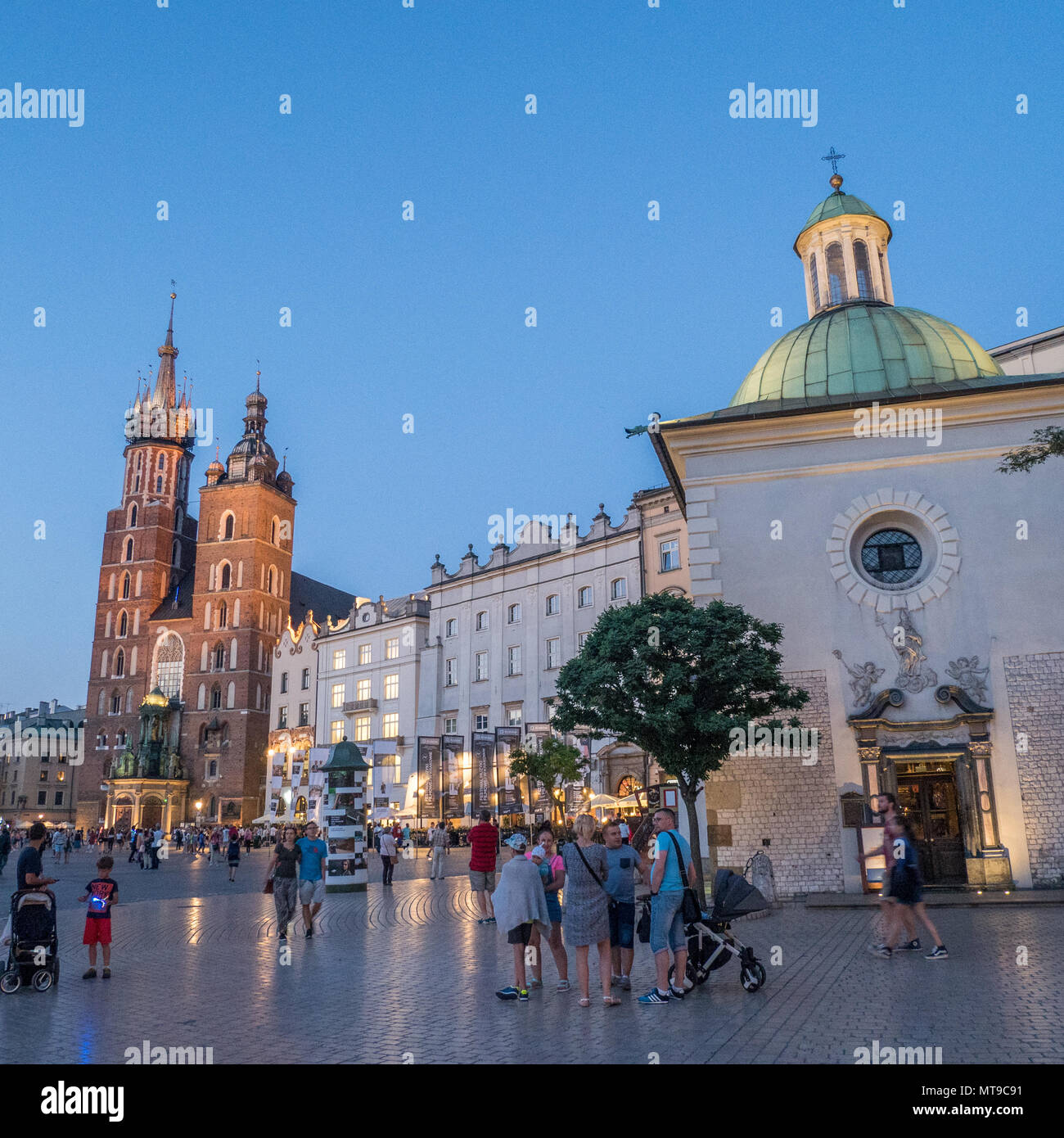 (Principal) Place du Marché médiéval dans la vieille ville de Cracovie en Pologne, avec l'église gothique en brique St Marys gauche. Banque D'Images