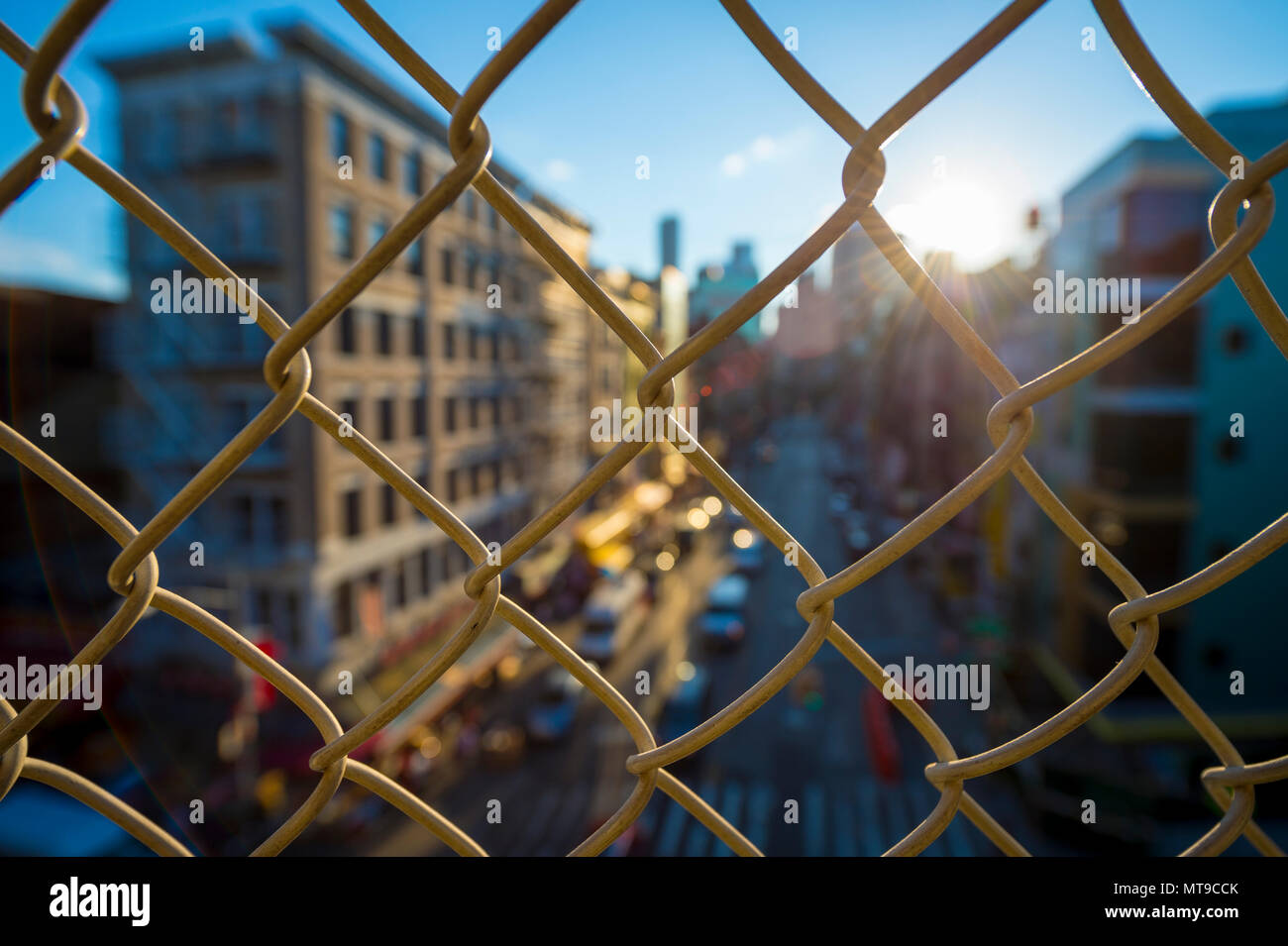 Le centre-ville de Manhattan et de Chinatown vue à travers une clôture de grillage simple torsion au coucher du soleil sur le pont de Manhattan. Banque D'Images