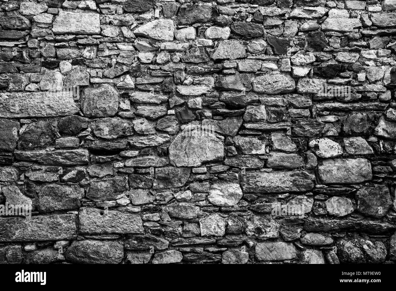 La texture d'un vieux mur de pierres de taille différente. Image en noir et blanc Banque D'Images