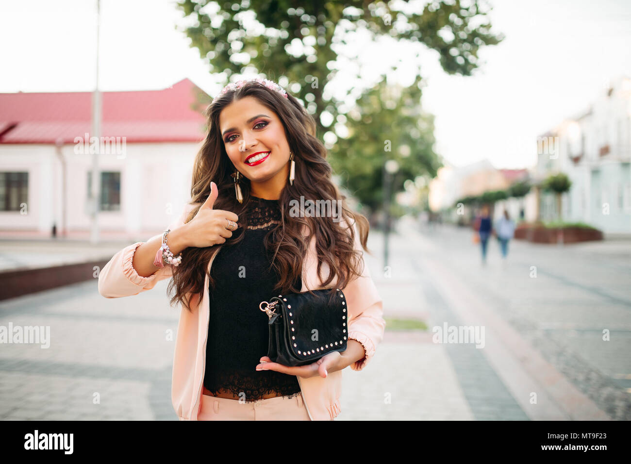 Beautiful happy girl avec sac à main noir à la mode showing thumb up. Banque D'Images