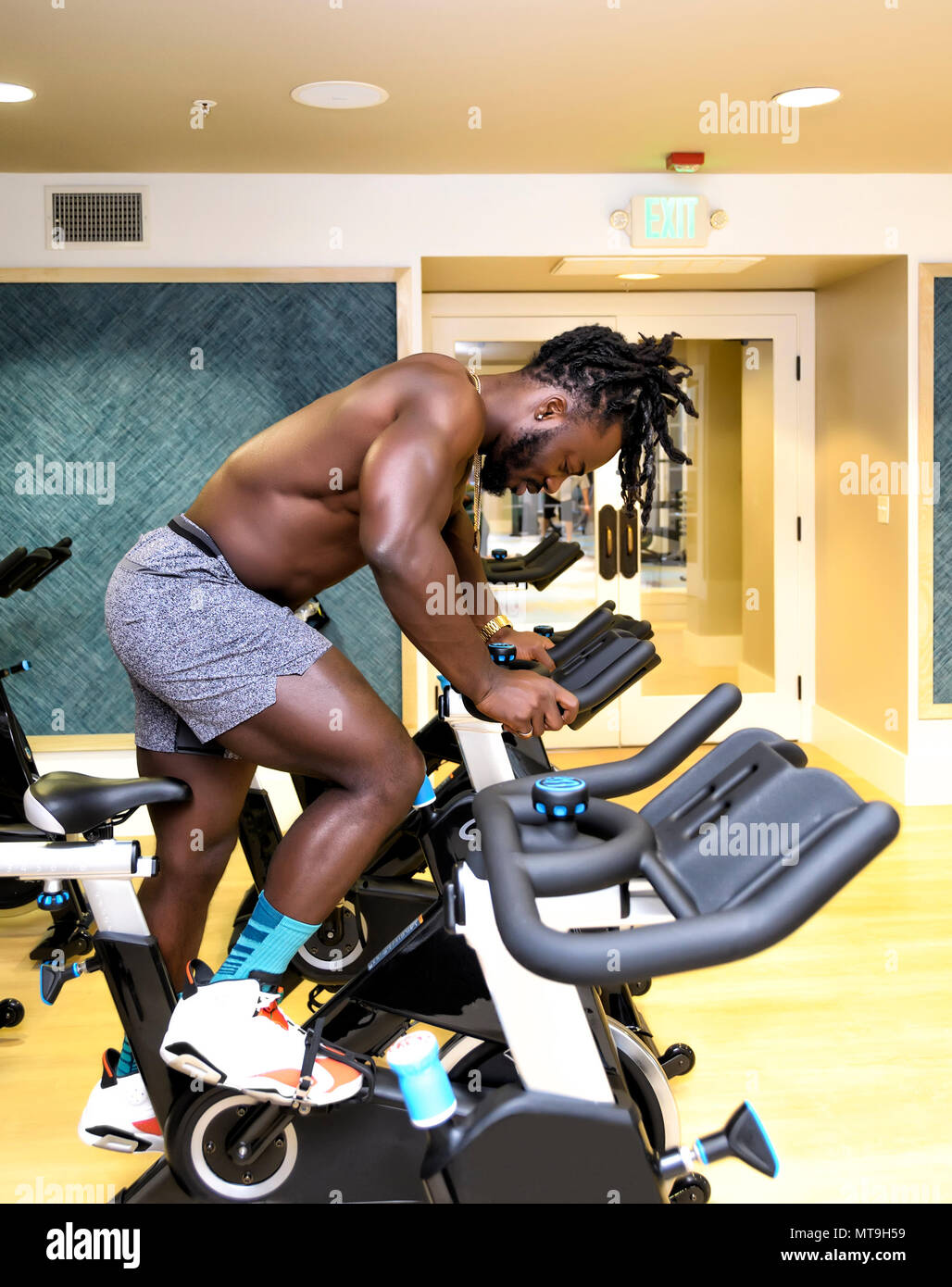 Beau, jeune, musclé African American man, un bodybuilder, école comme un vélo dans la salle de sport. Banque D'Images