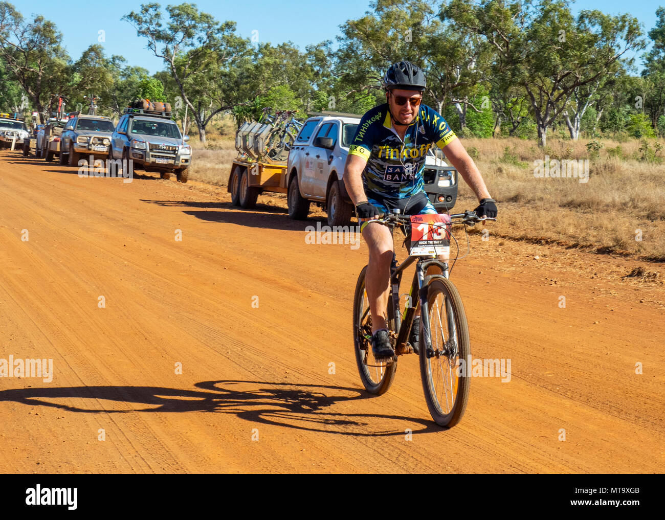 Un cycliste en vtt équitation passé un convoi de véhicules de soutien sur la Gibb River Road de saleté sur le Défi 2018 Gibb, Kimberley WA, Australie. Banque D'Images