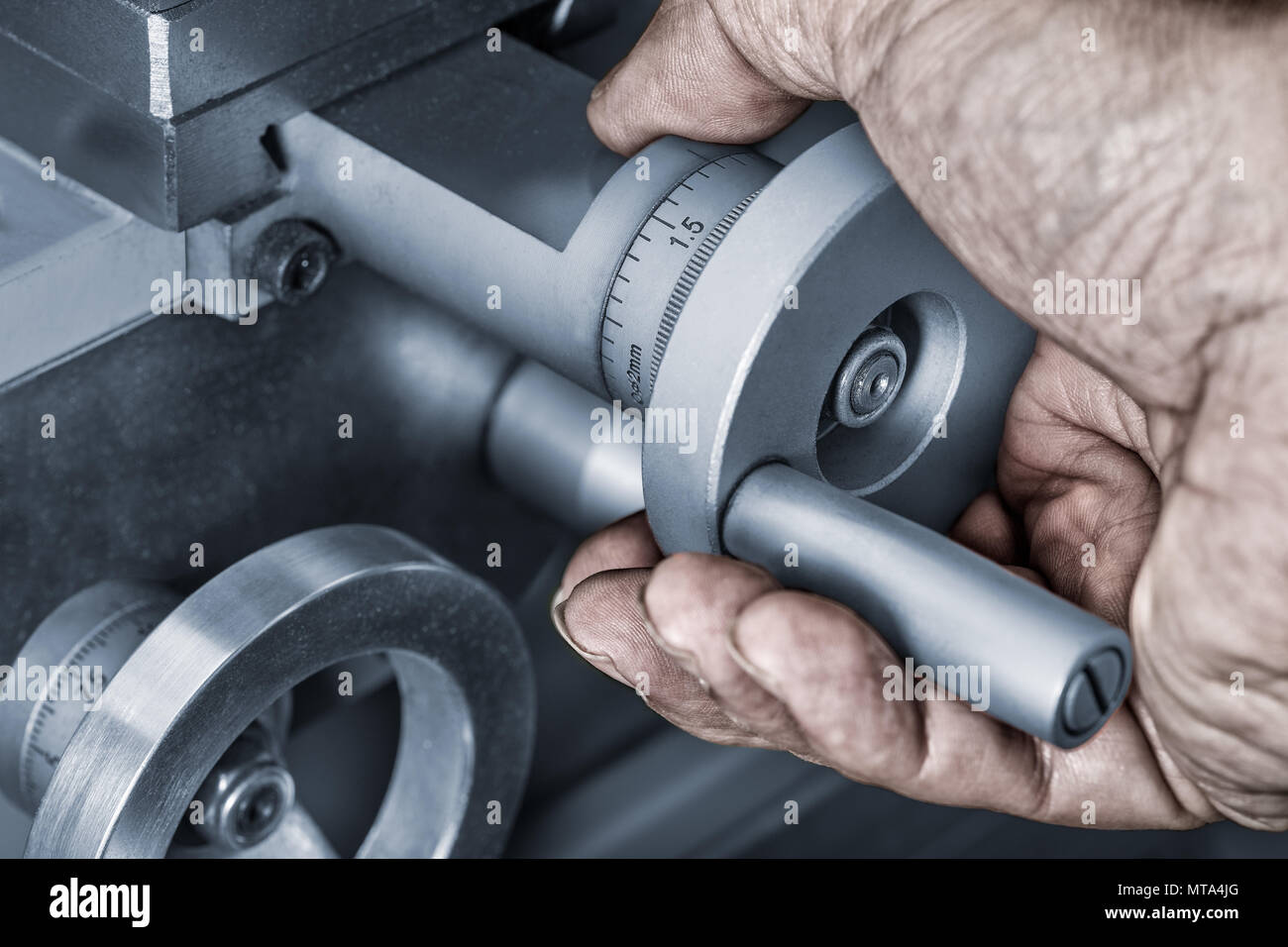 Close-up de roues de contrôle de l'avance sur une machine-outil. Détail d'une sale main sur le bouton de métal avec un vernier pour une mesure exacte. Banque D'Images