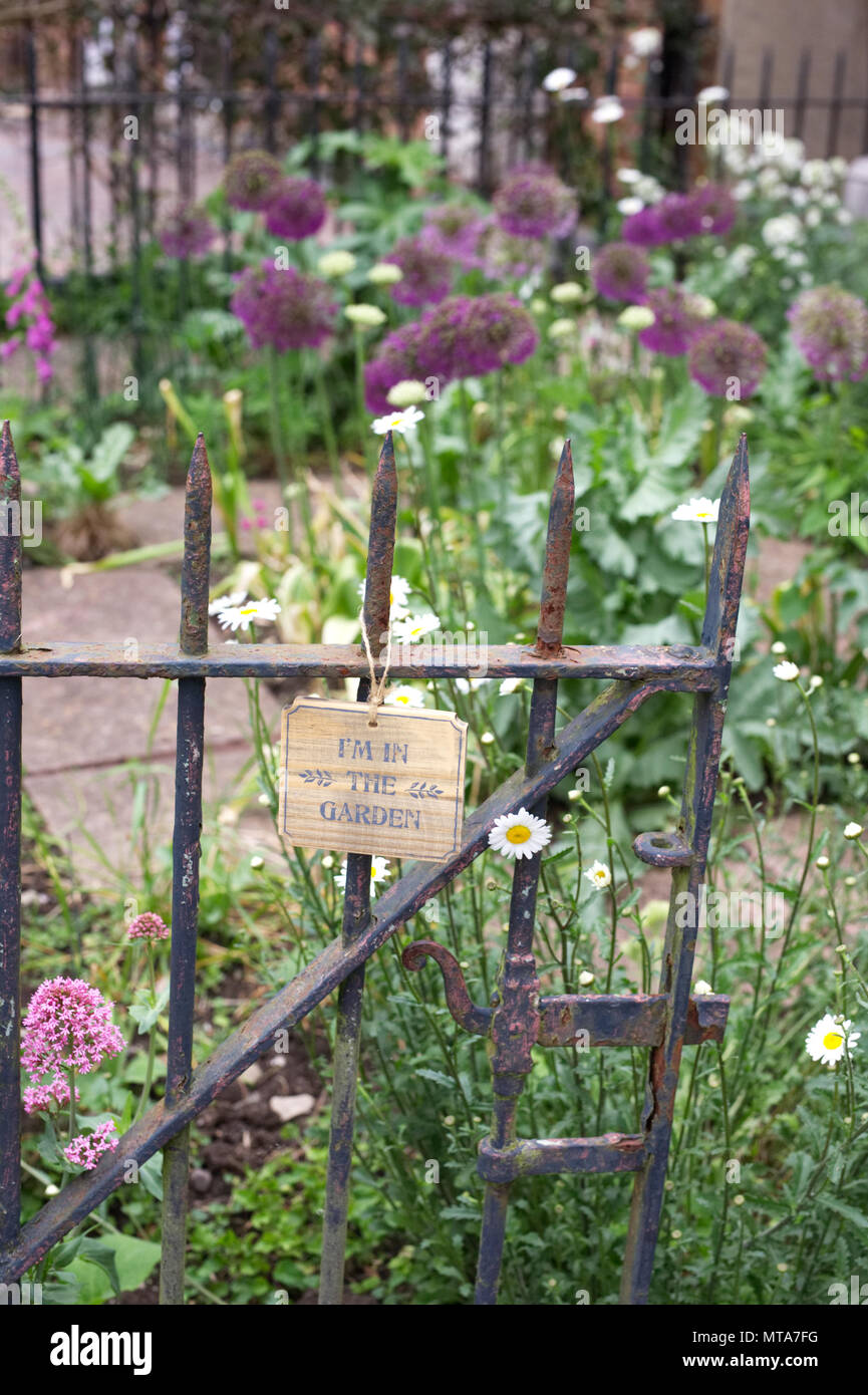 'Je suis dans le jardin" signe sur une vieille grille rouillée dans un jardin à l'avant. Banque D'Images