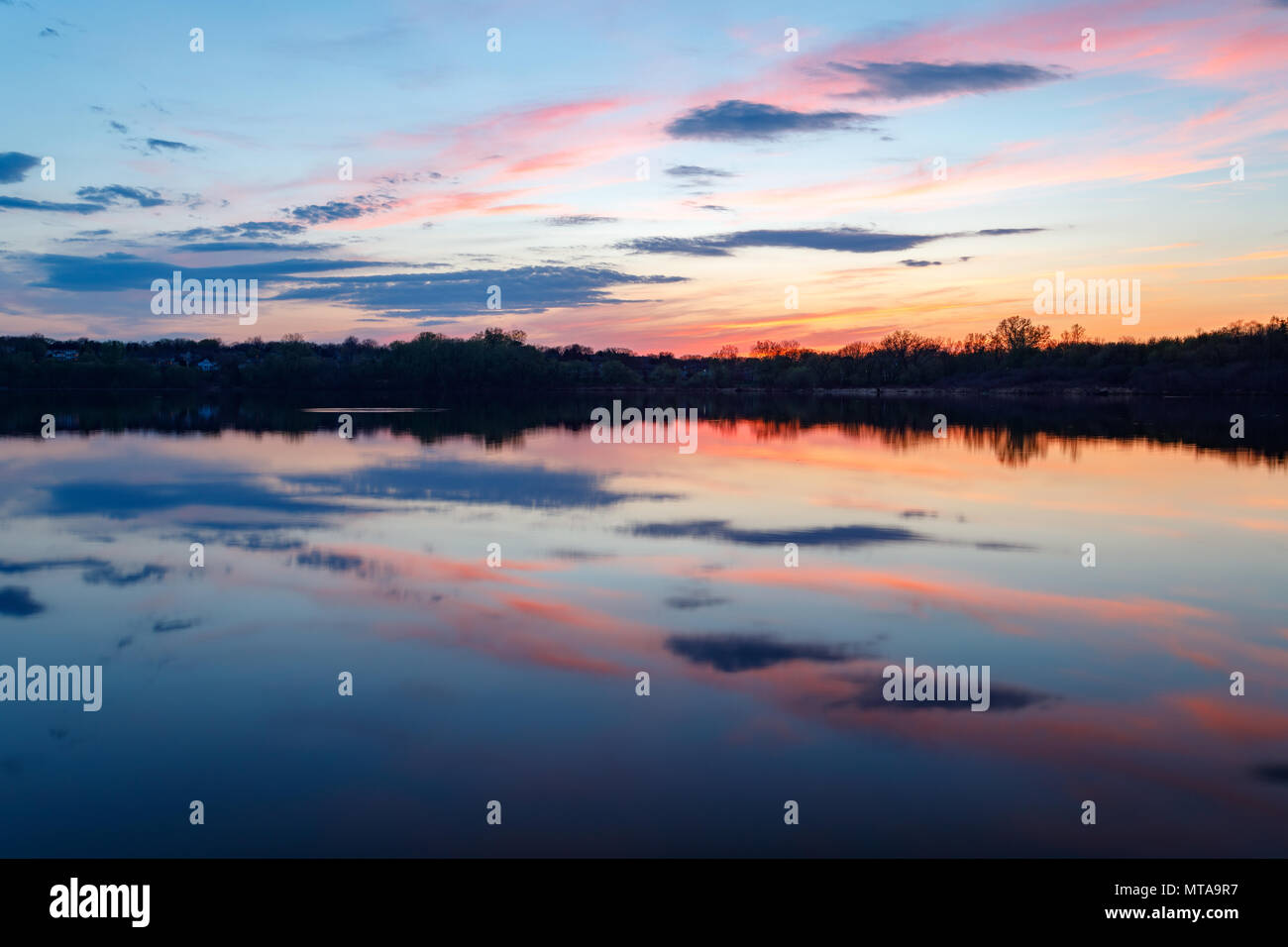 Les nuages colorés se reflètent sur le lac regardant au coucher du soleil. Eden Prairie, Minnesota. Banque D'Images