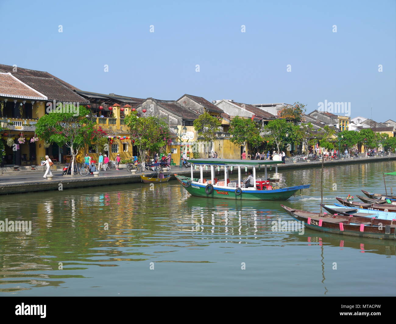 HOI AN, VIETNAM - 19 mars 2018 : Belle journée à l'ancienne ville de Hoi An avec vue sur les bateaux traditionnels, maisons au bord de la rivière jaune, et les touristes Banque D'Images HOI AN, VIETNAM - 19 mars 2018 : Belle journée à l'ancienne ville de Hoi An avec vue sur les bateaux traditionnels, maisons au bord de la rivière jaune, et les touristes Banque D'Images