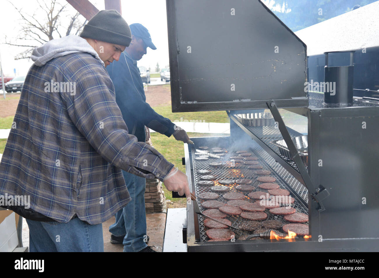 Hamburgers grill bénévoles au Sun Plaza Park pendant la journée des sports le 21 avril 2017, à la Malmstrom Air Force Base, au Montana, aviateurs, a pris une pause de la manifestations sportives pour participer à des hamburgers et des rafraîchissements qui ont été servis pour le déjeuner. Banque D'Images