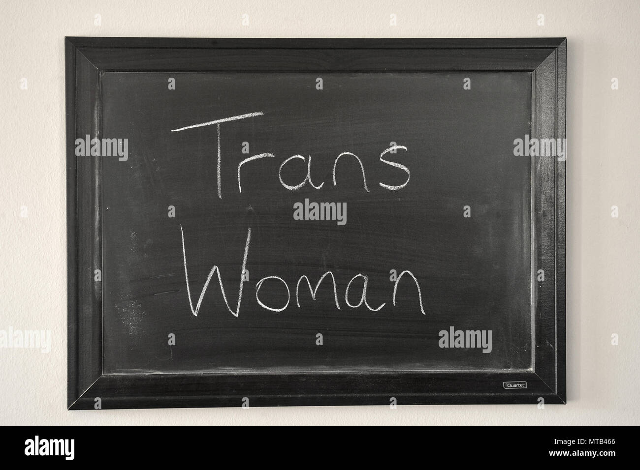 Trans femme écrit dans une craie blanche sur un tableau noir fixé au mur Banque D'Images
