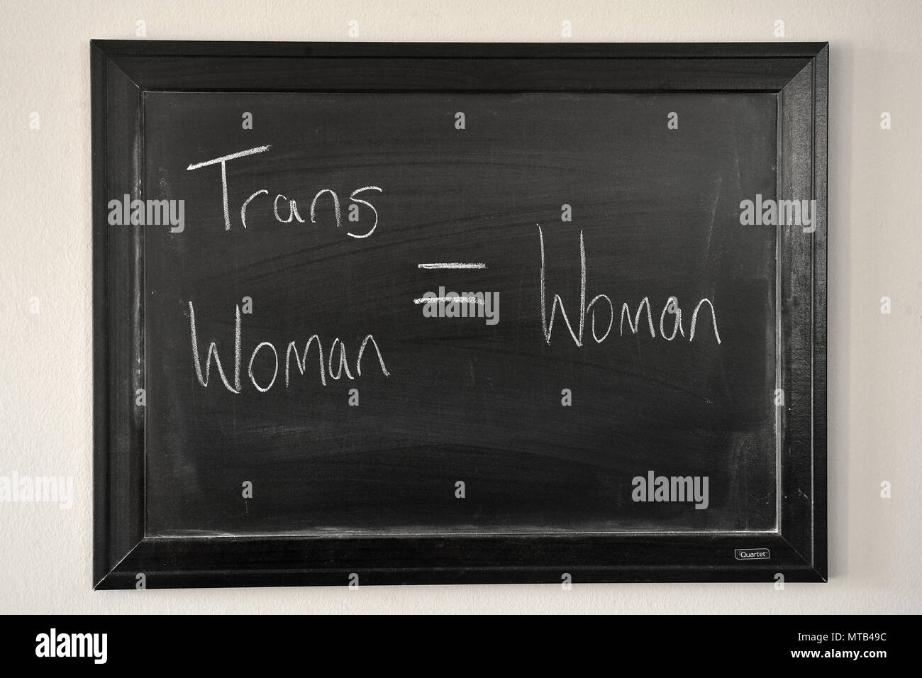 Trans femme = femme écrit dans une craie blanche sur un tableau noir fixé au mur Banque D'Images