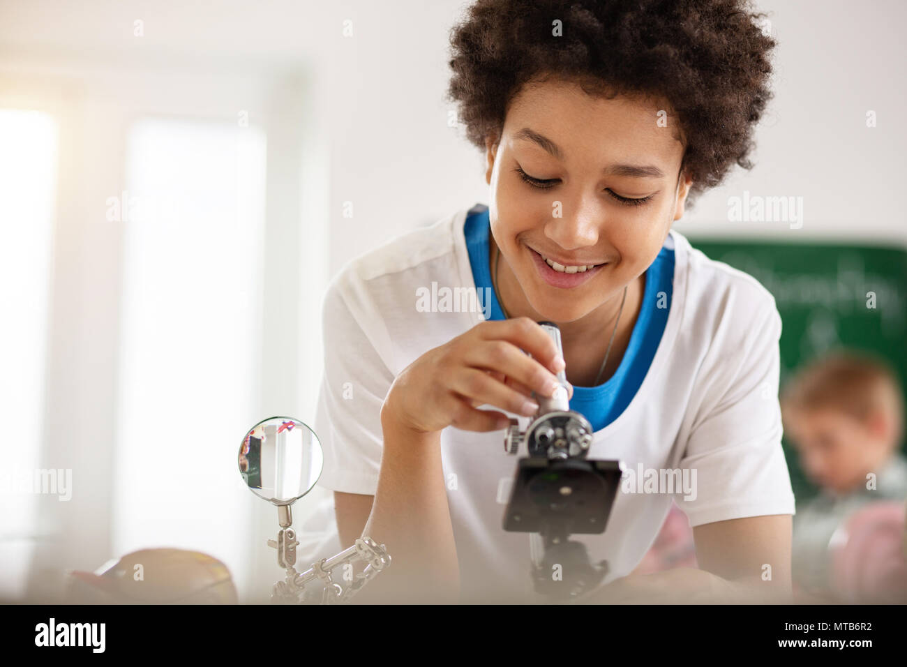 Garçon à la recherche positive intelligente dans le microscope Banque D'Images