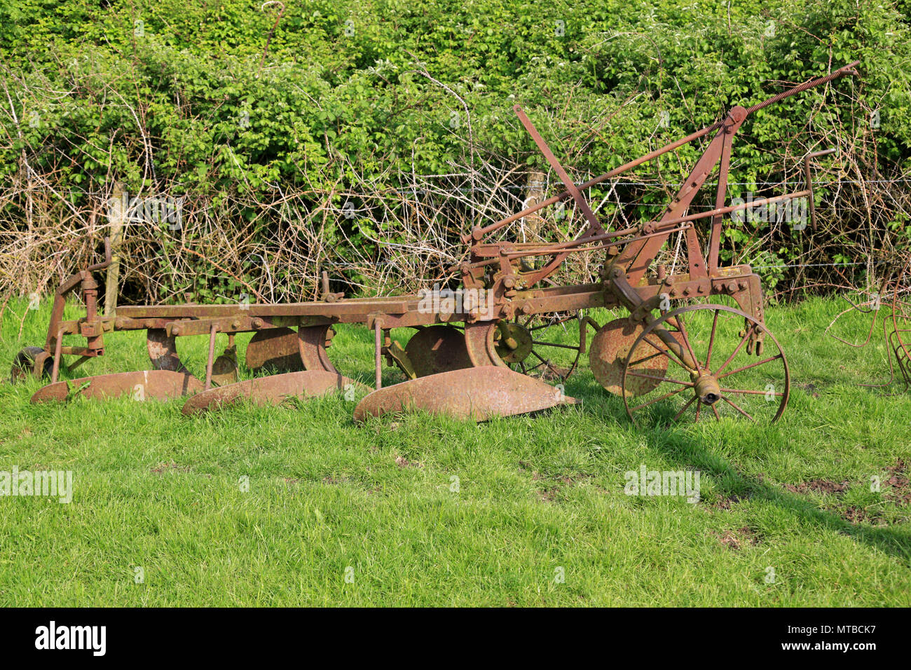 Rusty old farm machinery abandonnés dans un champ dans le Gloucestershire, Angleterre, Royaume-Uni. Banque D'Images