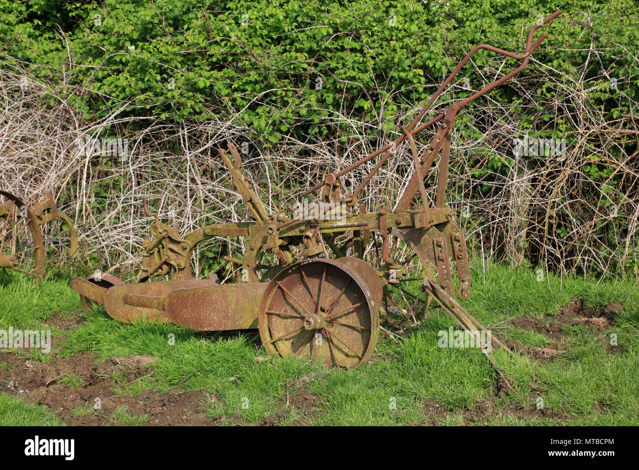 Rusty old farm machinery abandonnés dans un champ dans le Gloucestershire, Angleterre, Royaume-Uni. Banque D'Images