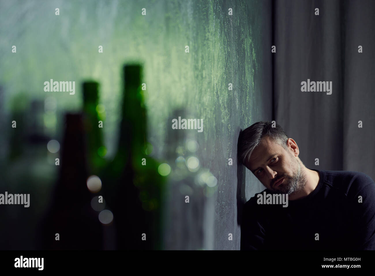 L'homme souffrant de dépression avec des bouteilles d'alcool vides Banque D'Images