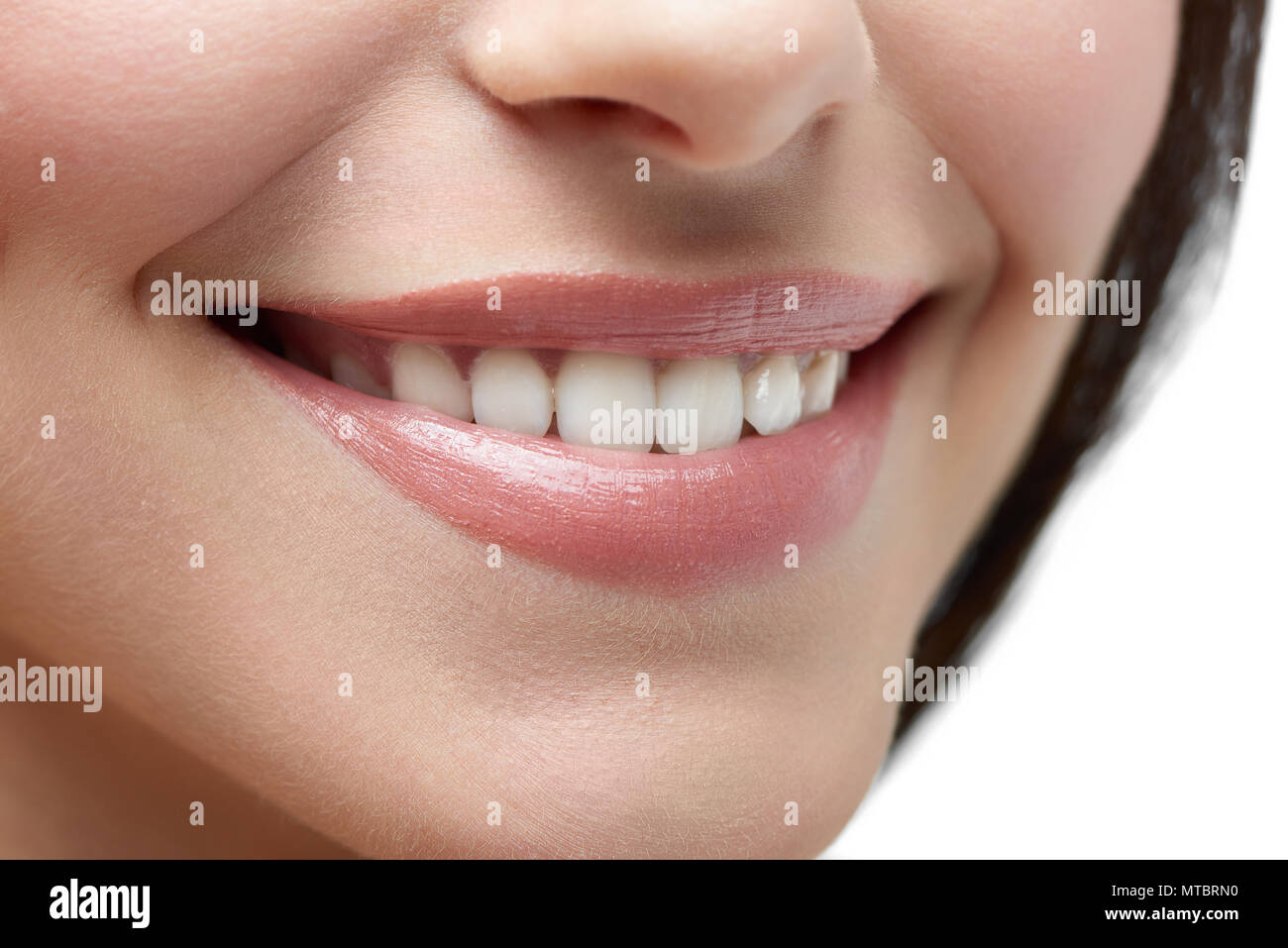 Close up Studio de modèle est beau sourire sur fond blanc. Une peau douce et saine, dents blanches, lèvres roses dodus, petit nez et des cheveux brun foncé sur arrière-plan. Beau sourire. Banque D'Images