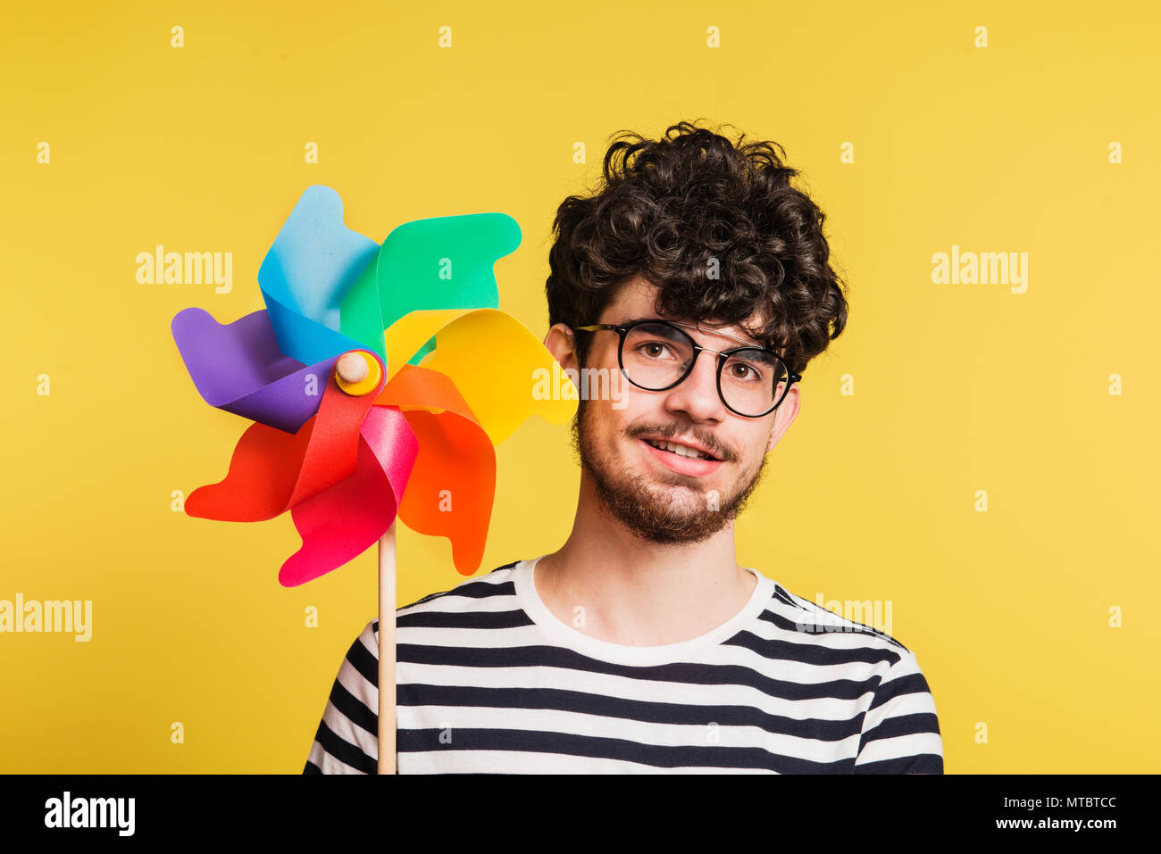 Portrait d'un jeune homme tenant un moulin sur un fond jaune. Banque D'Images