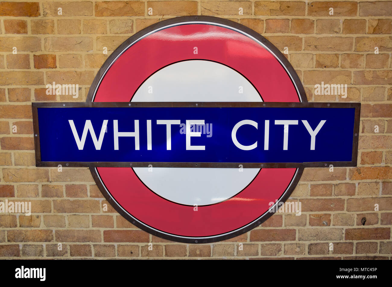 L'iconic London Undergound de son enseigne, monté sur un mur de brique à White City Station. Banque D'Images