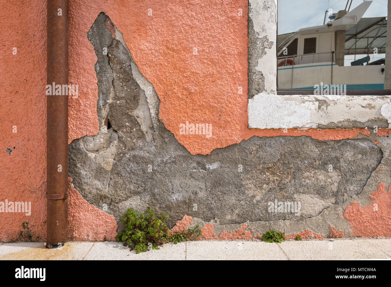 Plâtre émietté d'un mur orange, la réflexion d'un bateau dans la fenêtre, port de Cres (Croatie) Banque D'Images