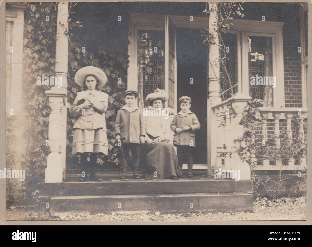 Carte de Cabinet victorien d'une dame et ses enfants sur le porche de leur maison Banque D'Images