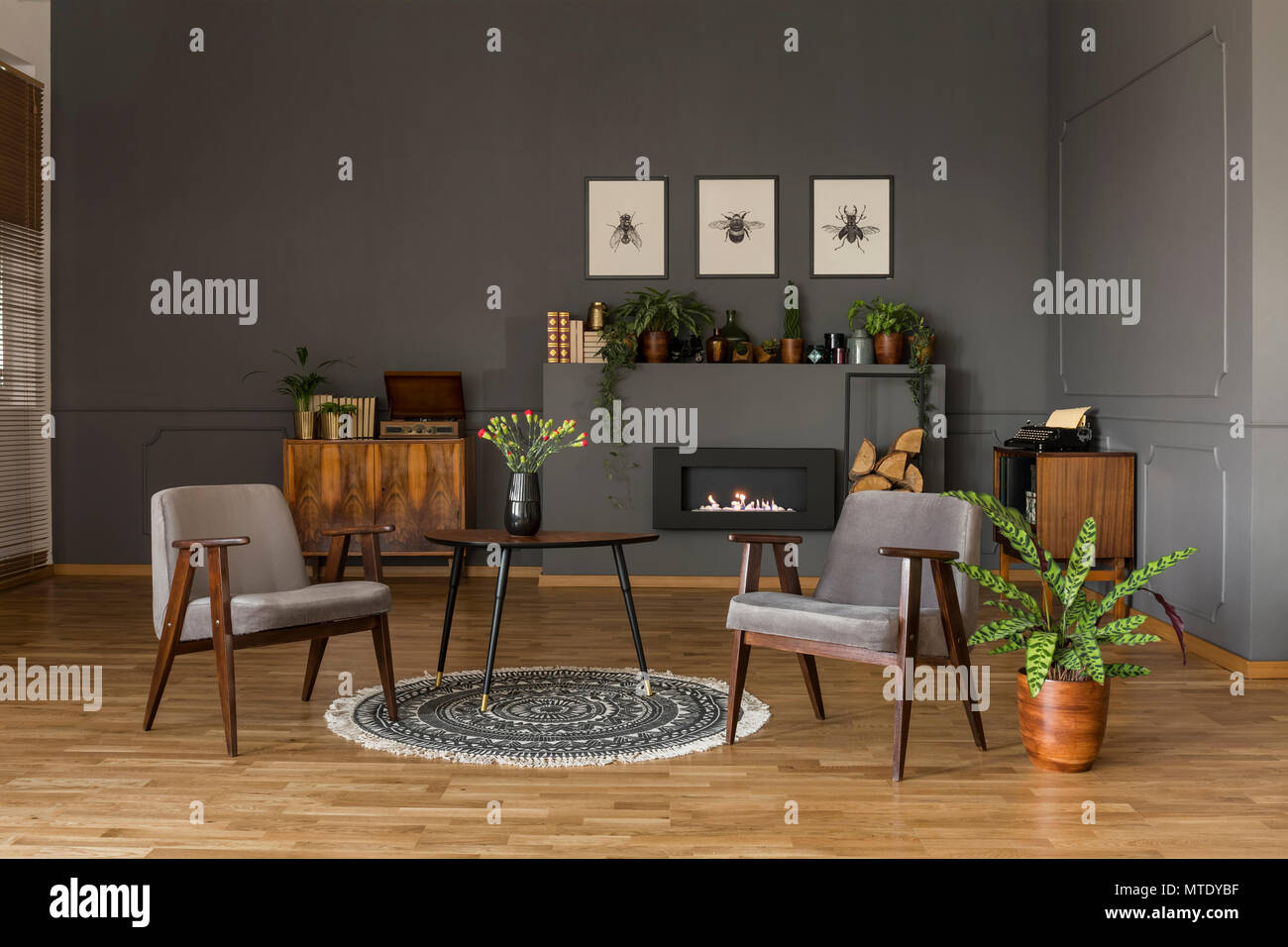 Table avec des fleurs sur un tapis gris entre les fauteuils en rétro salon intérieur avec plante. Photo réelle Banque D'Images