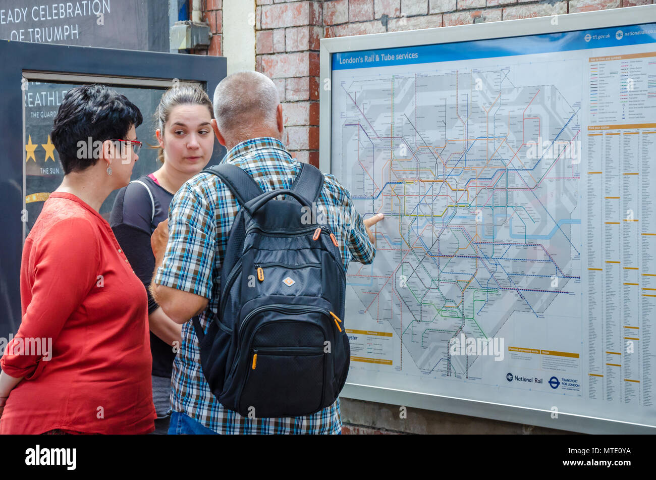 Une famille consulter une carte du métro de Londres à la station Hammersmith pour aider à naviguer jusqu'à leur destination. Banque D'Images