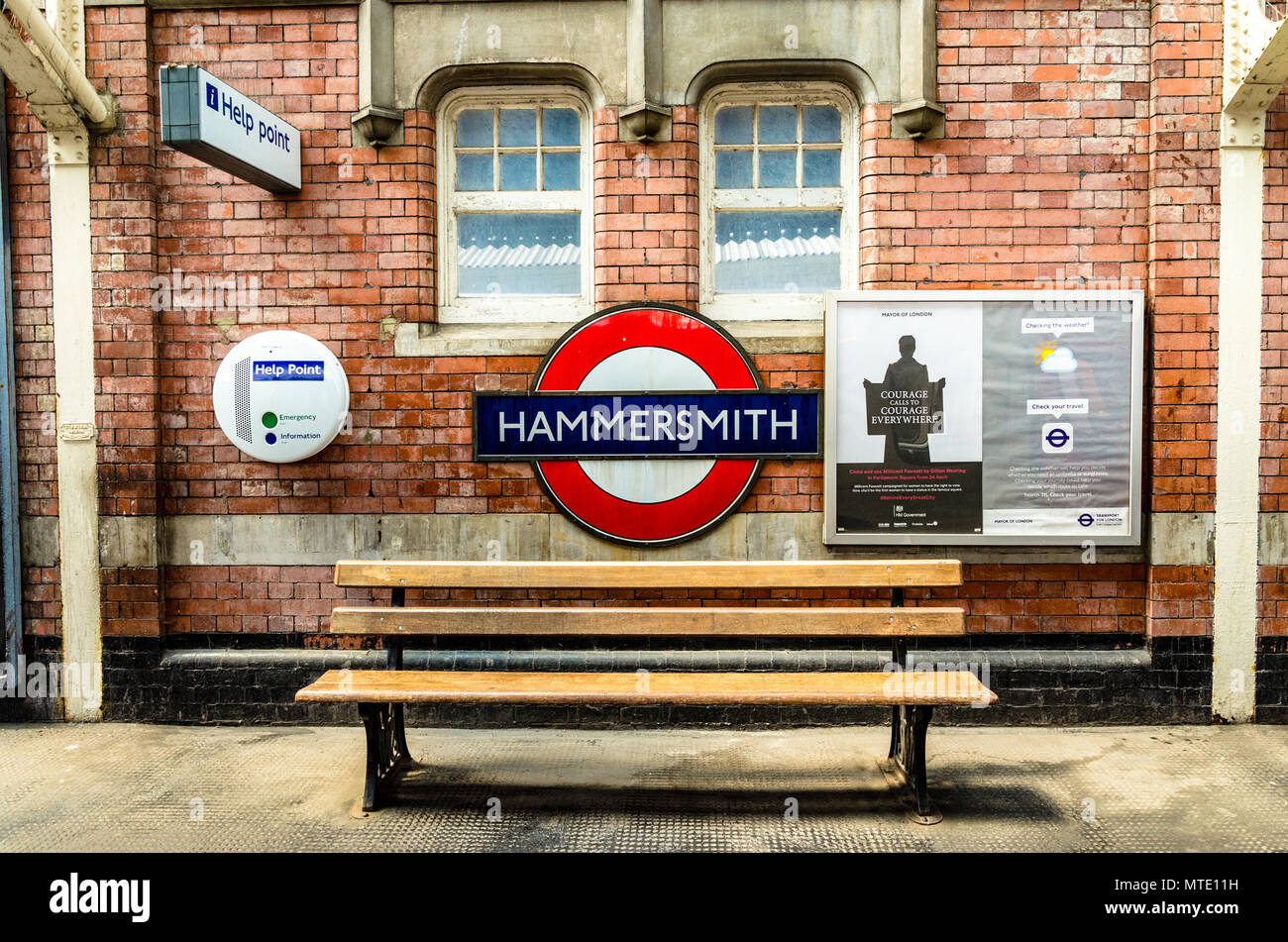La station de métro emblématique enseigne de Hammersmith sur un mur vide au-dessus d'un banc en bois. Banque D'Images
