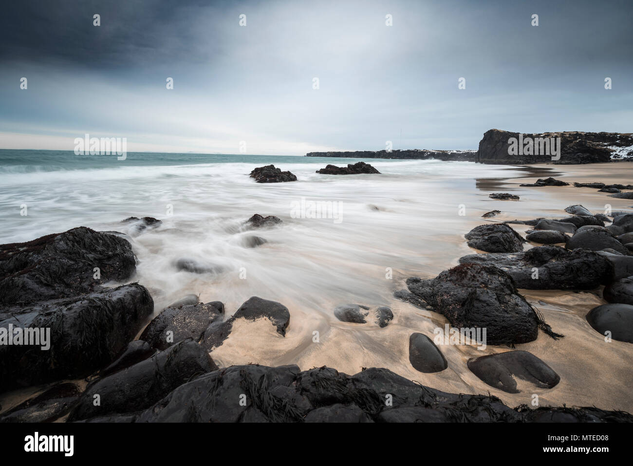 Skarðsvík Beach, plage de sable avec des grosses roches volcaniques noires, les vagues à la mer, le mauvais temps, l'exposition de l'ampoule, à l'ouest de l'Islande Banque D'Images