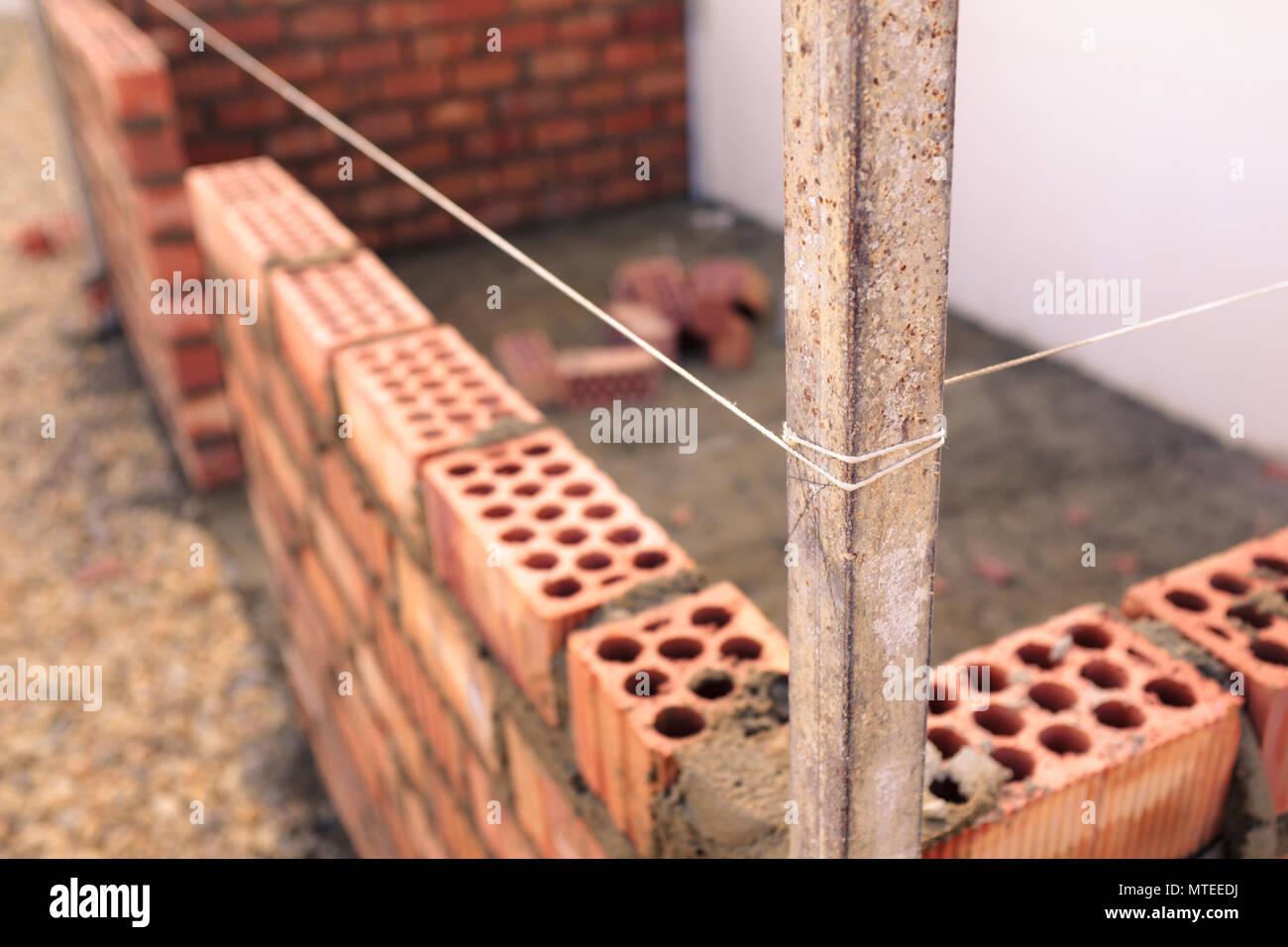 String utilisé comme un niveau dans la construction d'un mur d'un petit bâtiment de briques Banque D'Images