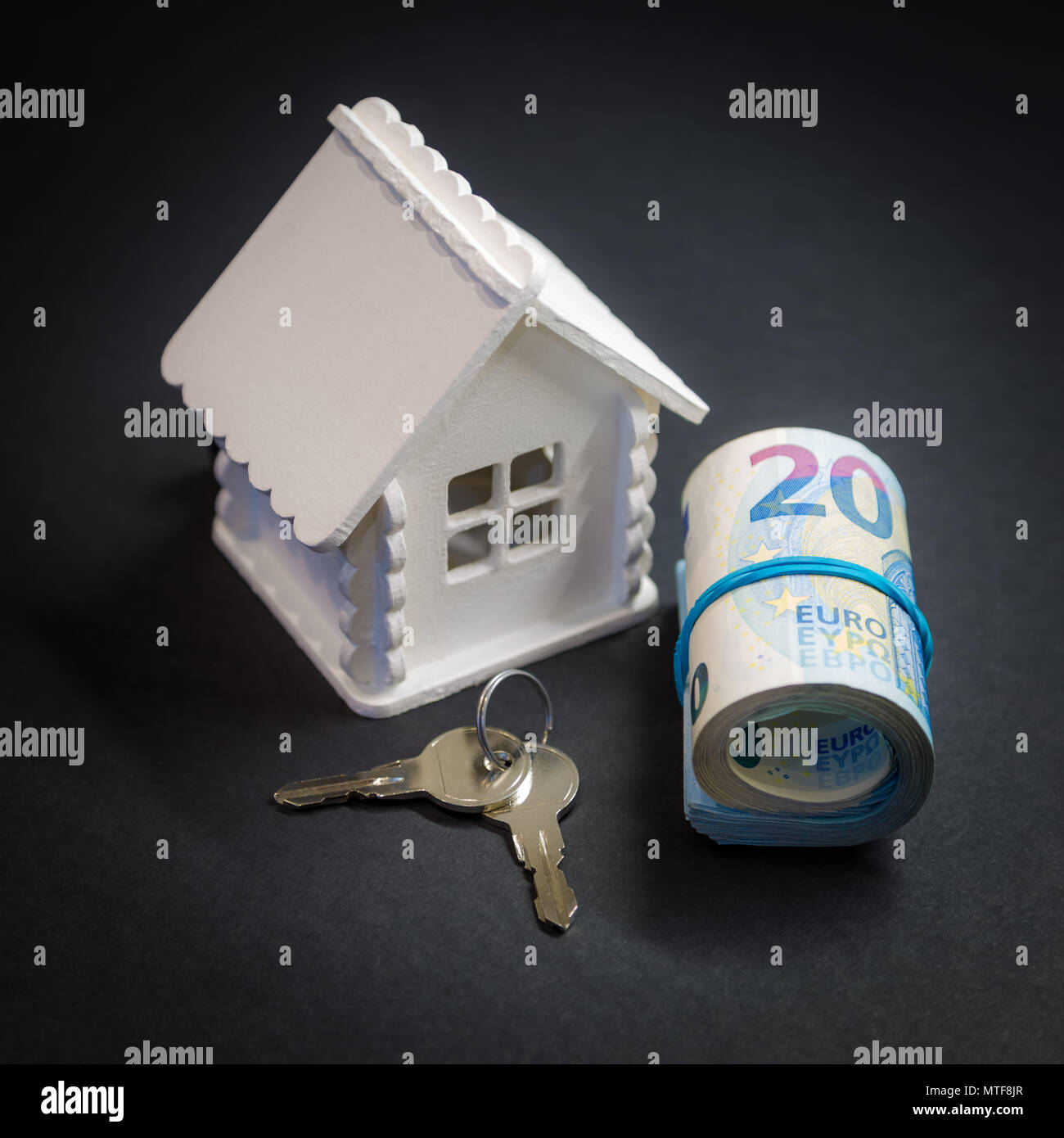 Maison de jouets, deux clés de la maison et un rouleau d'argent d'une valeur de 20 euros Banque D'Images