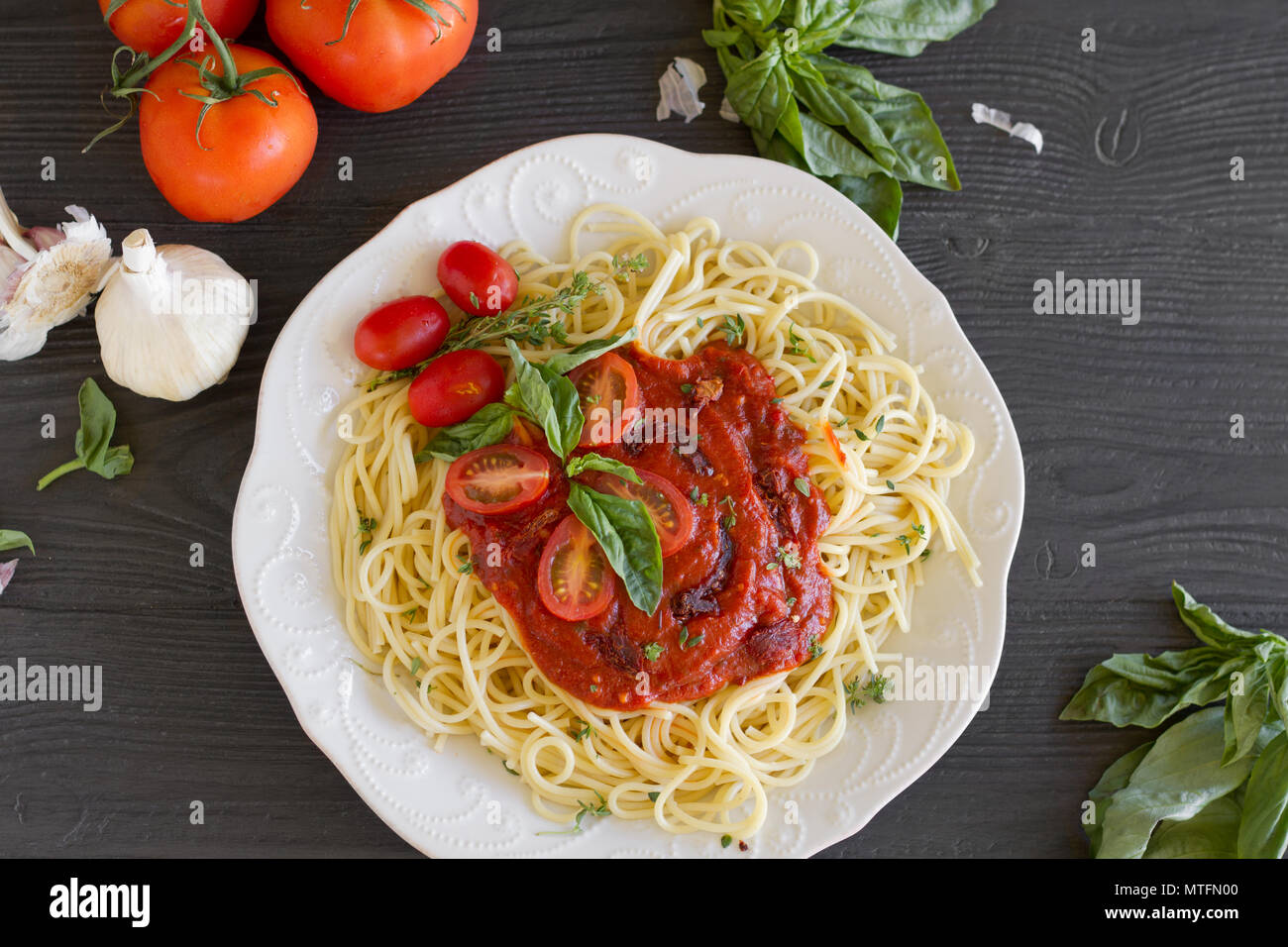 Les pâtes spaghetti avec sauce tomate rouge, le basilic, l'ail et les tomates en vigne. Banque D'Images