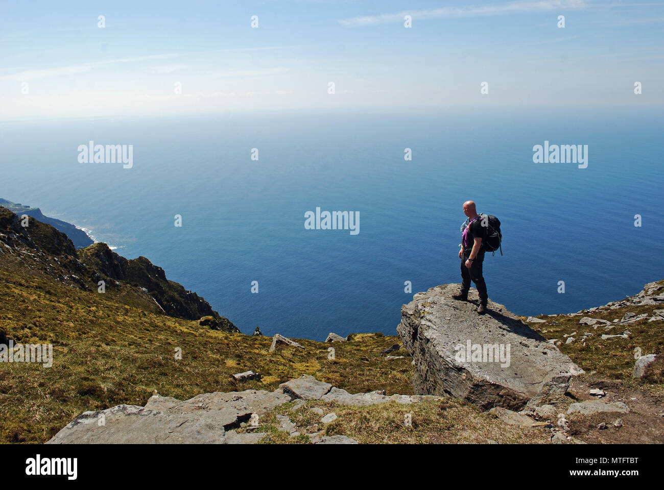 Un randonneur donne sur la mer du haut des falaises de Slieve League, dans le comté de Donegal. Banque D'Images