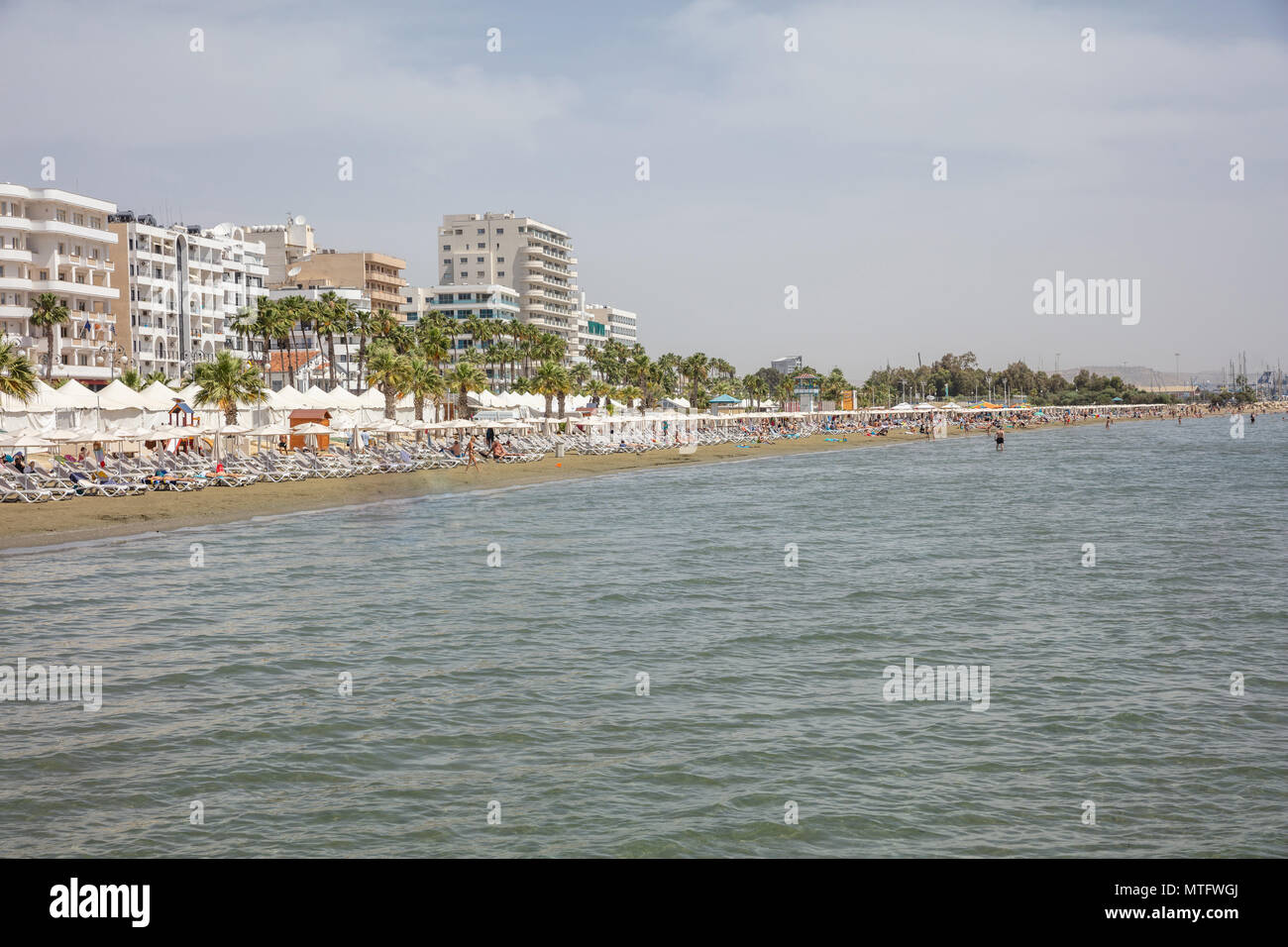 Chypre, Larnaca à l'été. Bâtiments à plusieurs étages en bord de mer, plage de sable, mer et ciel bleu Banque D'Images