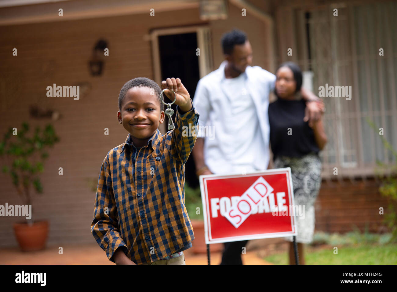 Boy holding keys en face de new house Banque D'Images