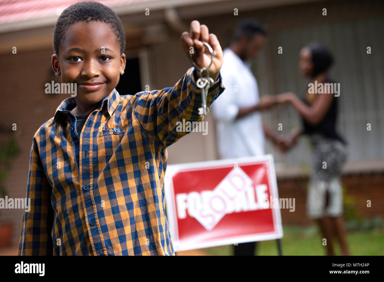 Boy holding keys en face de new house Banque D'Images