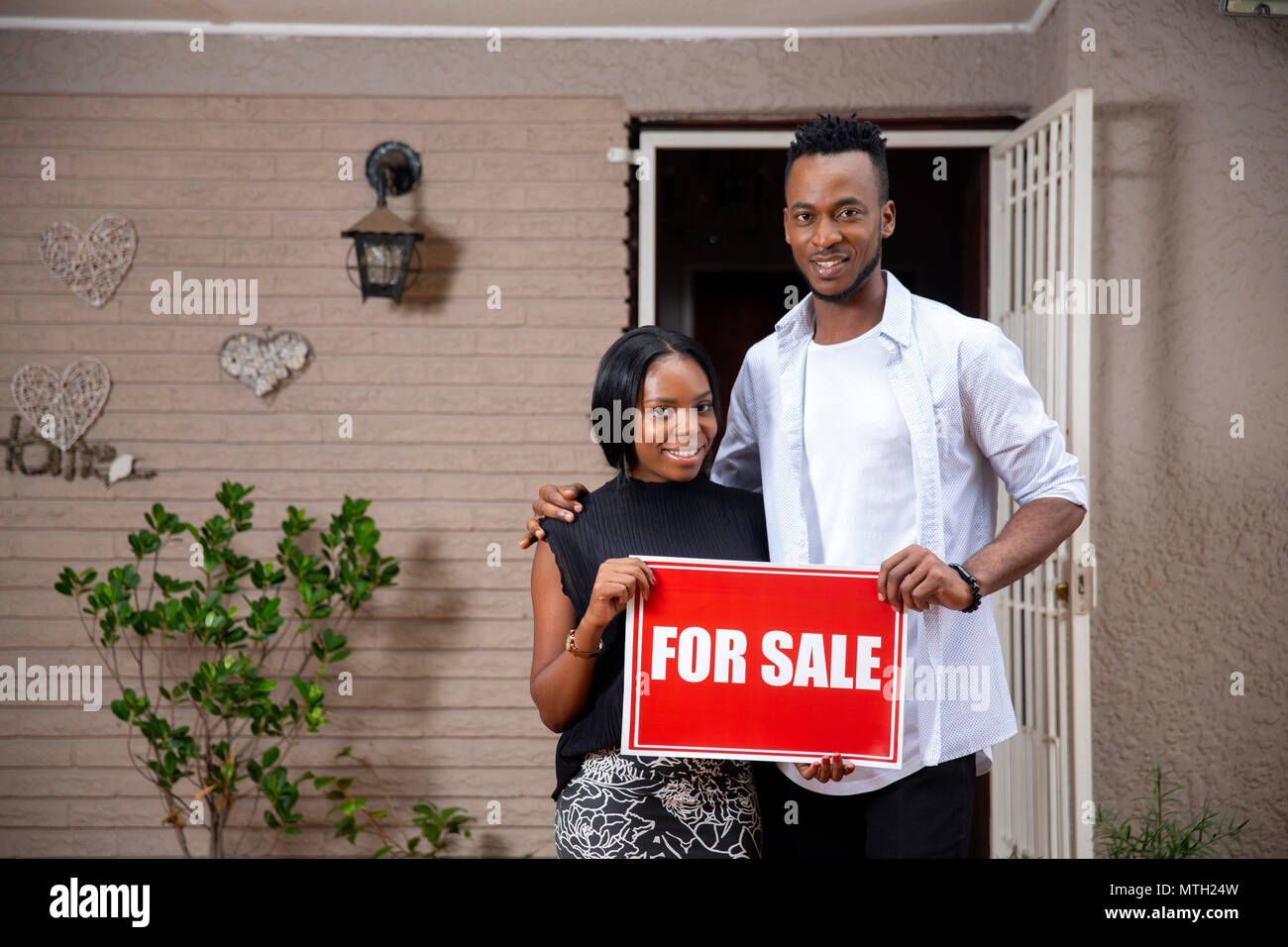 Couple standing in doorway holding For Sale sign Banque D'Images