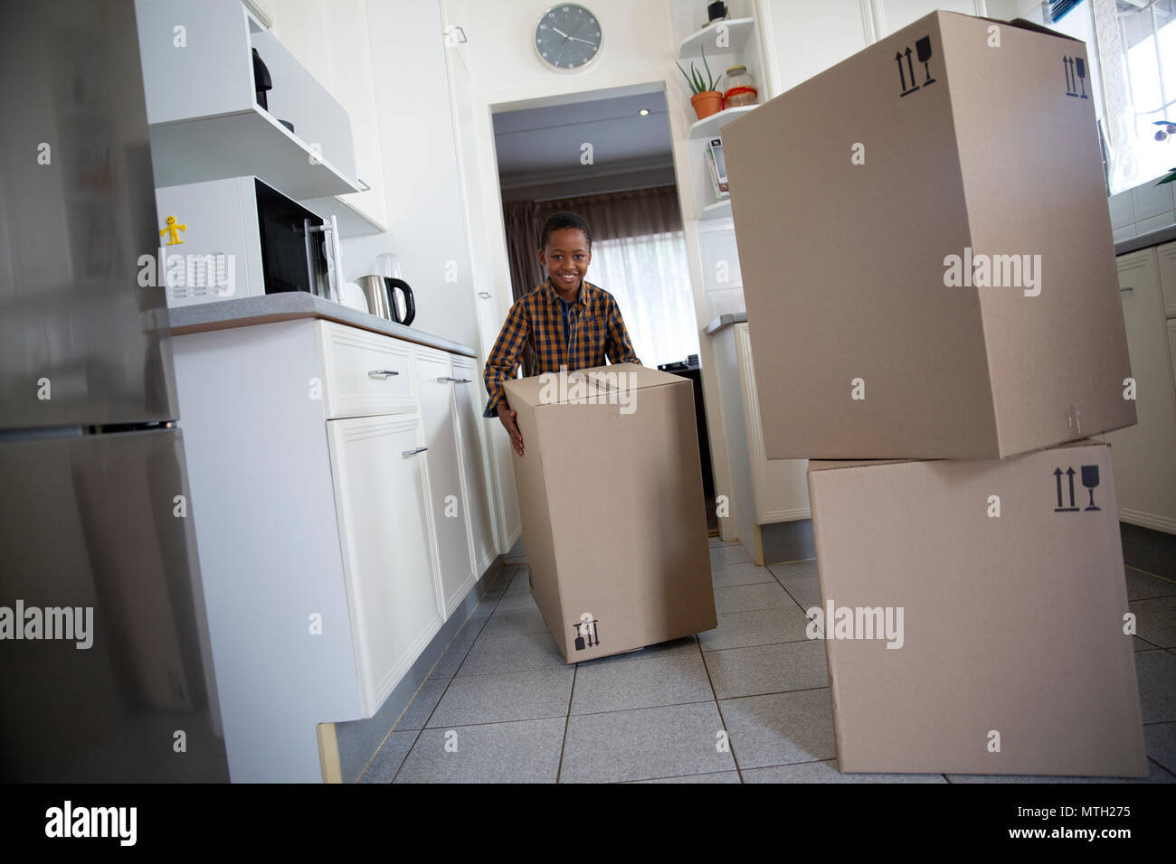 Boy moving boxes en cuisine Banque D'Images