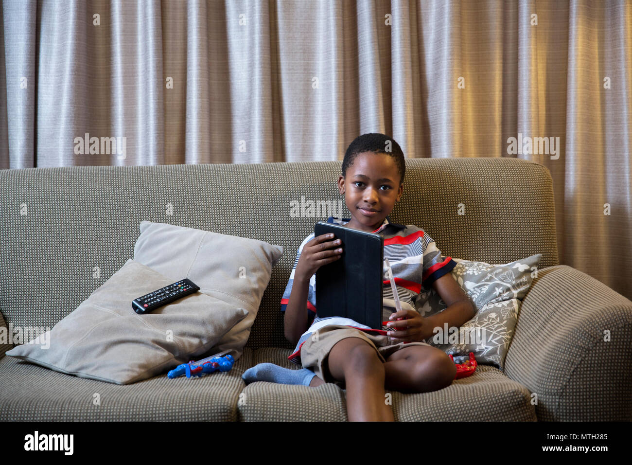 Garçon jouant sur tablet on couch Banque D'Images