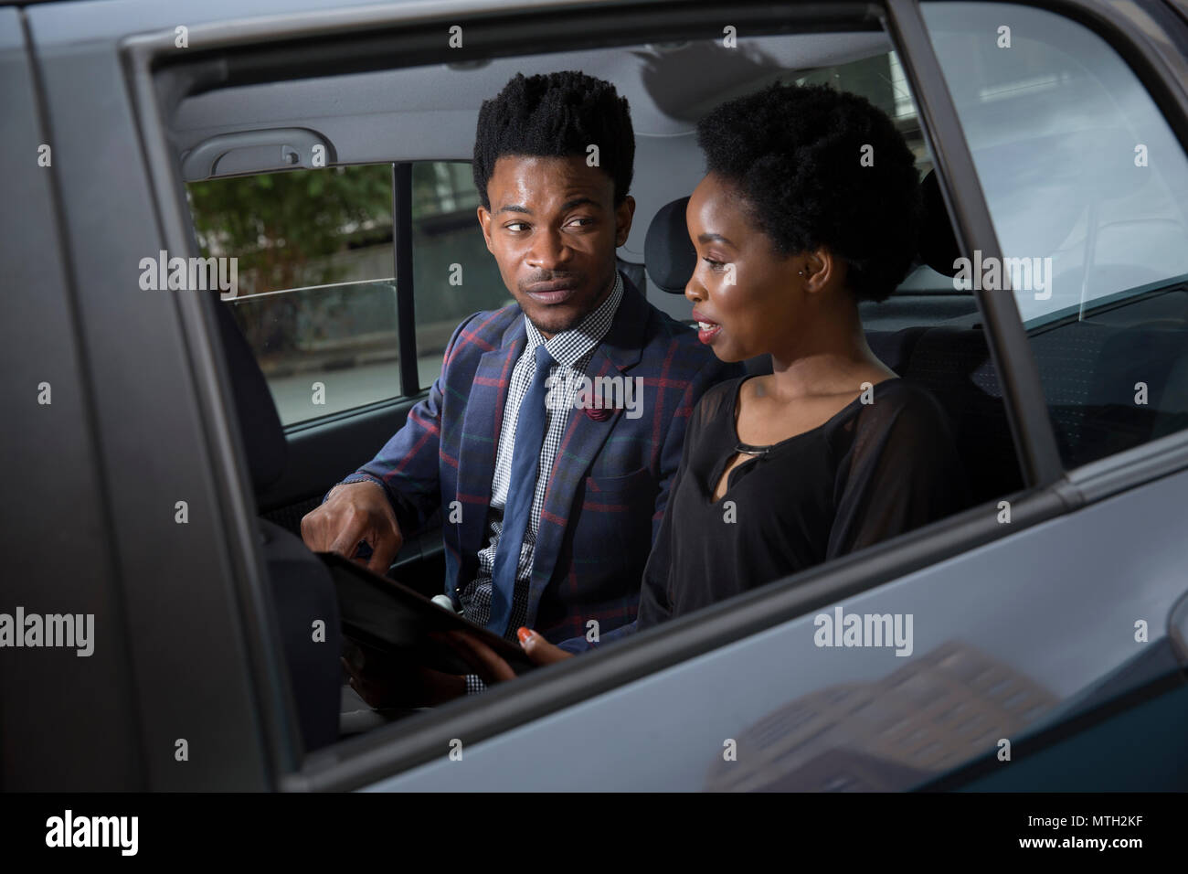 L'homme d'affaires et femme assise sur le siège arrière de la voiture Banque D'Images