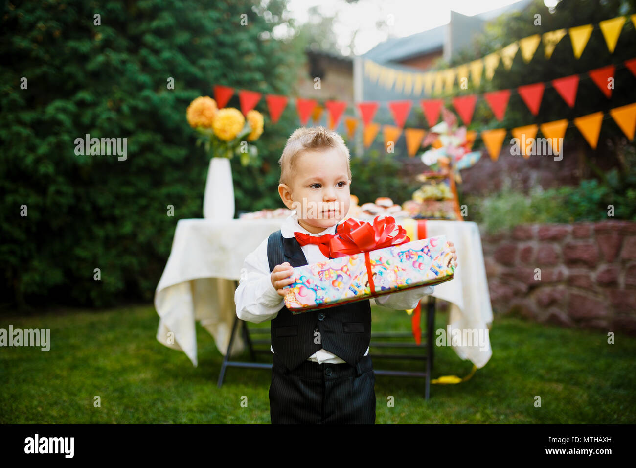 Surprise Pour L Anniversaire Le Garcon Est Maintenant Une Boite Avec Un Cadeau Dans La Cour Sur L Arriere Plan D Une Table De Fete Avec Un Gateau Vetu D Un Costume Noir Photo Stock Alamy