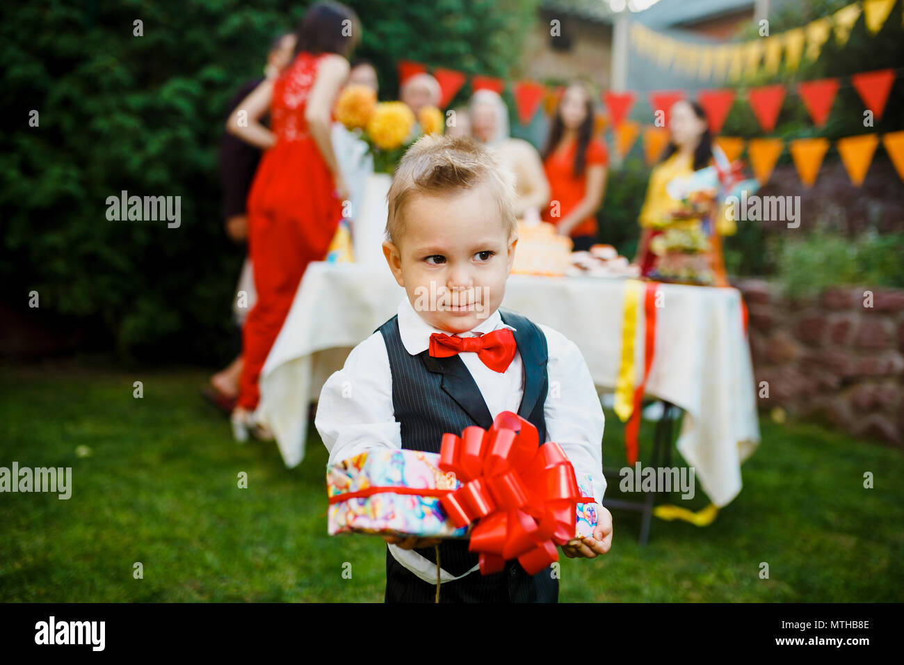 Maison De Vacances Enfants Theme Anniversaire Un Petit Garcon Se Tenant Dans La Cour De La Maison Avec Des Cheveux Blonds Vetu De Rouge Et Costume Papillon Avec Boite Cadeau Decorat Photo Stock
