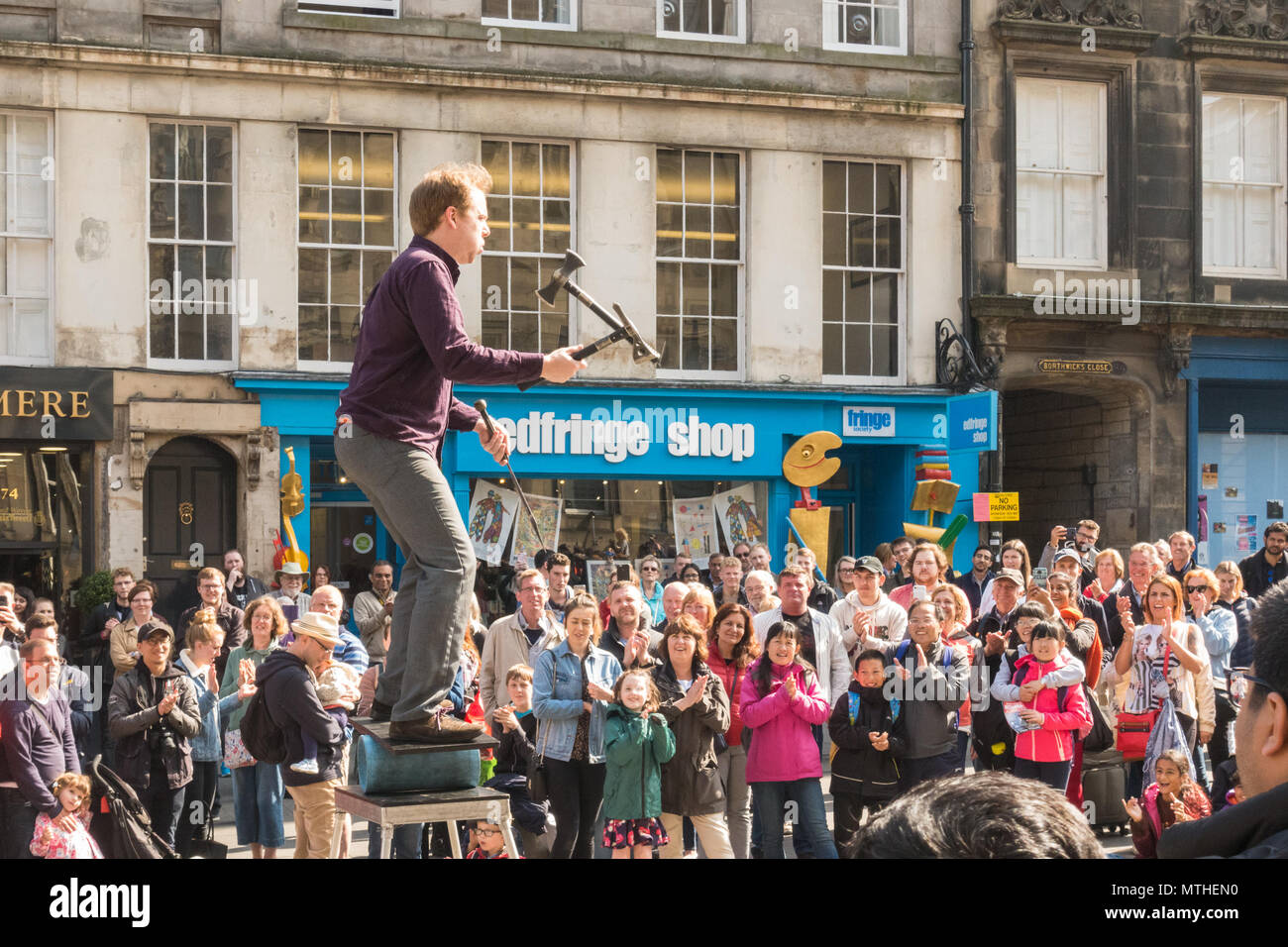 Artiste de la rue de sexe masculin jonglant avec un couteau et des haches tout en équilibrant en face de grande foule sur le Royal Mile d'Édimbourg, Écosse, Royaume-Uni Banque D'Images