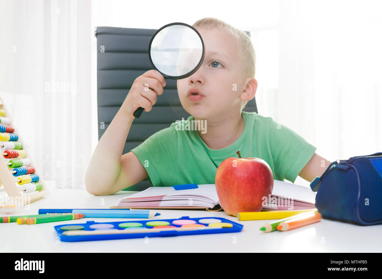 Enfant joue avec loupe. Enfant de l'école, petit garçon l'apprentissage à la maison. Concept de l'enseignement élémentaire Banque D'Images